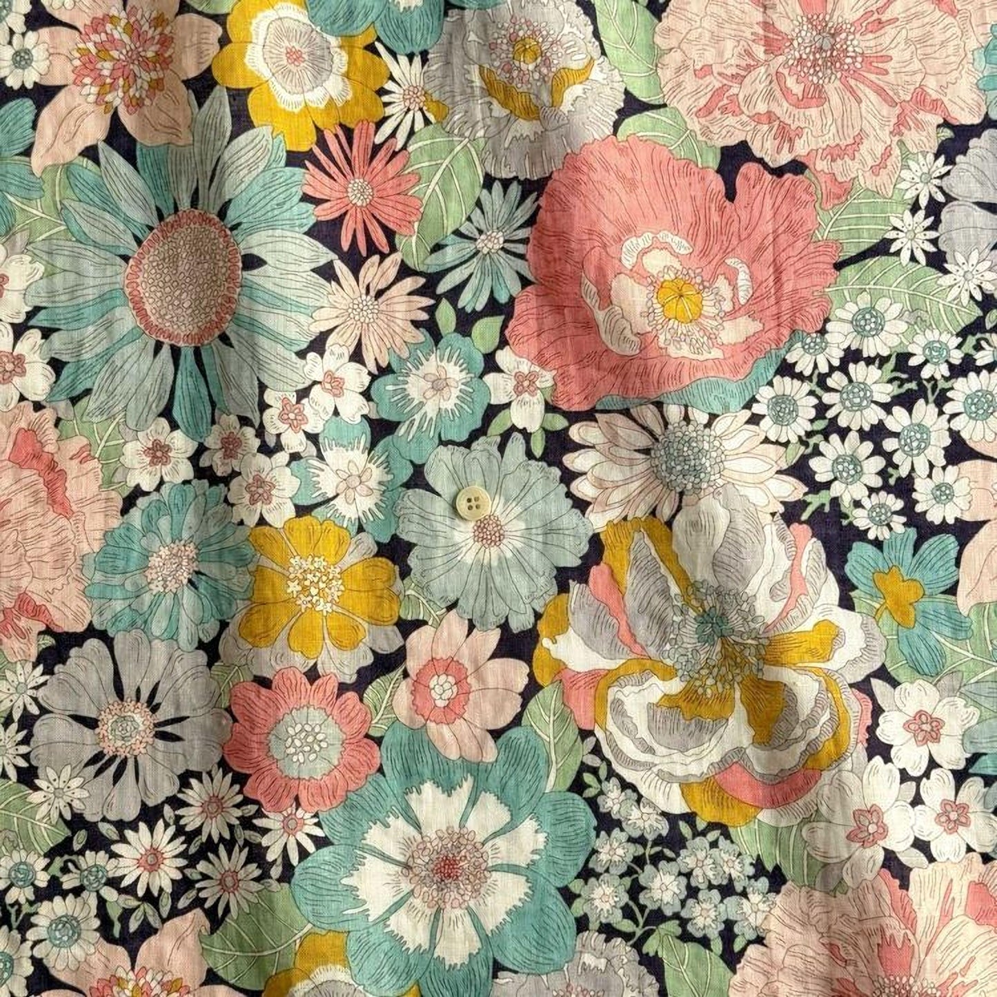 The image is a vibrant and colorful floral print featuring a variety of flowers in shades of pink, white, yellow, and green against a dark background.