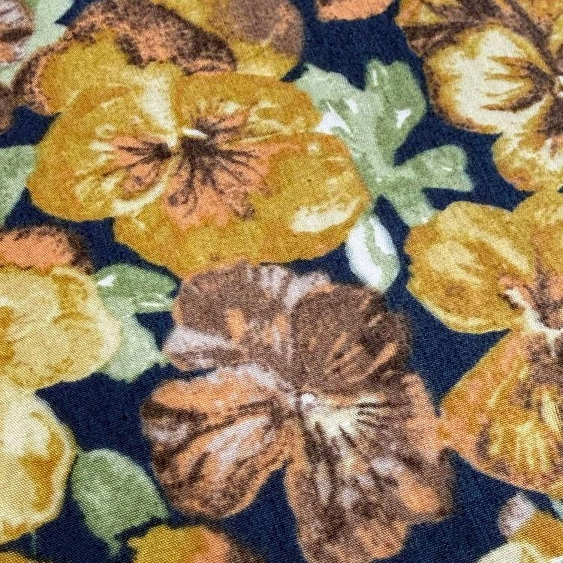 a close-up view of a fabric with a floral pattern, including yellow and brown flowers. The fabric appears to be dark blue, providing a contrasting background for the colorful flowers.