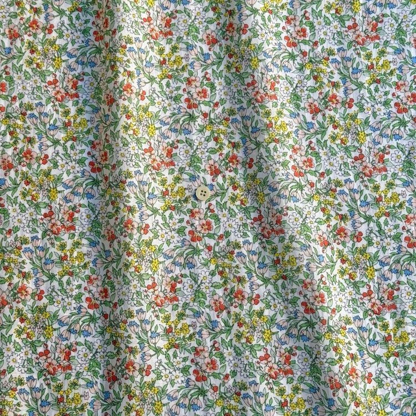 a close-up view of a fabric with a floral pattern, featuring a variety of colorful flowers and leaves.