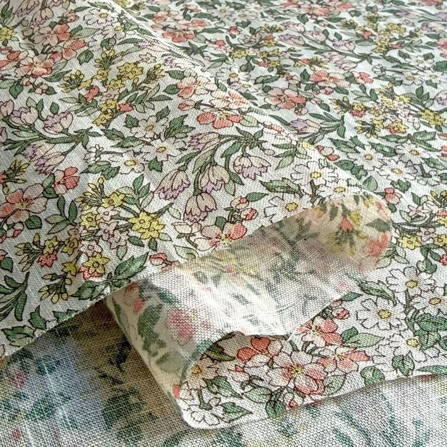 a close-up view of a fabric with a floral pattern, including various shades of green, pink, and yellow flowers.