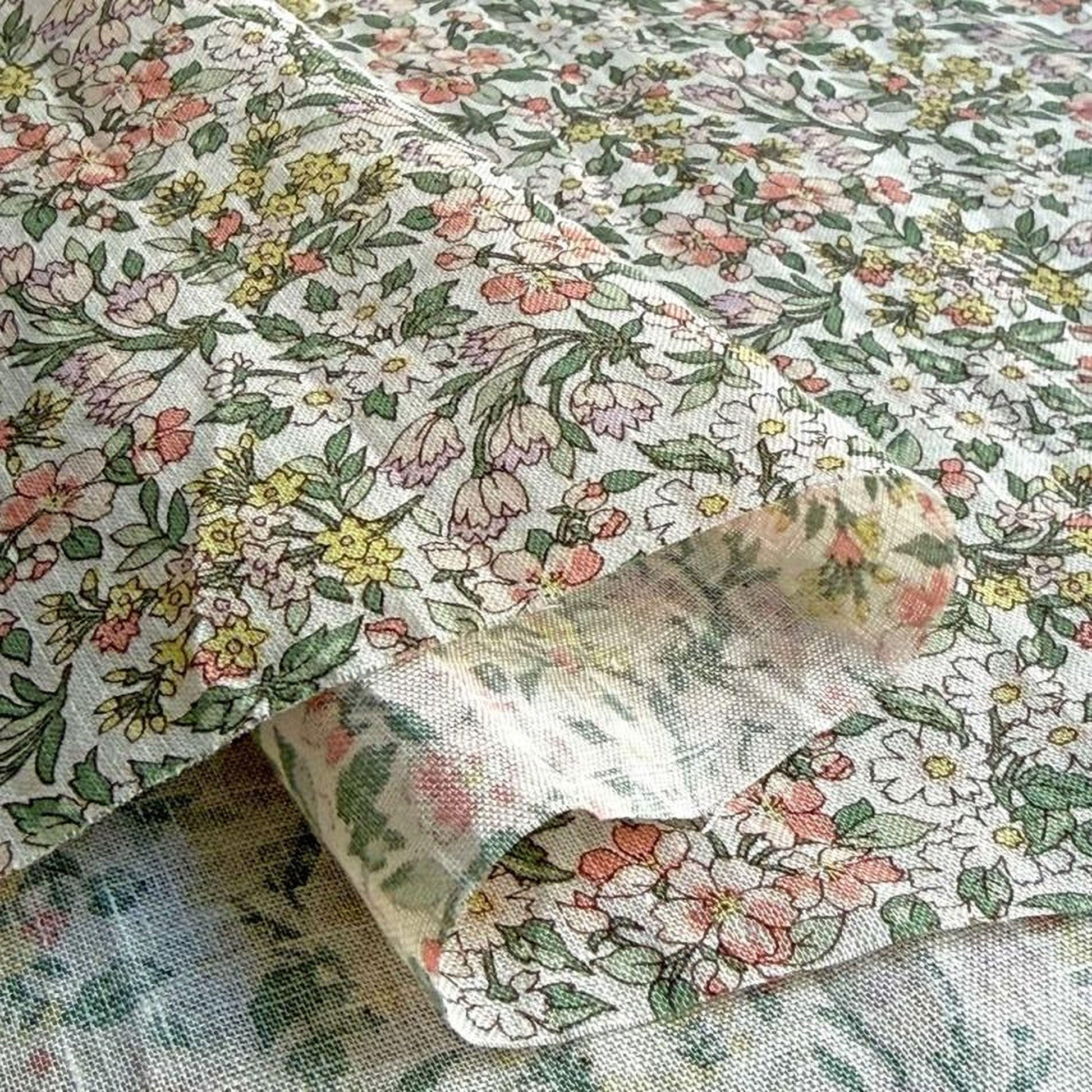 a close-up view of a fabric with a floral pattern, including various shades of green, pink, and yellow flowers.