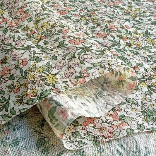 a close-up view of a fabric with a floral pattern, including various shades of green, pink, and yellow flowers.