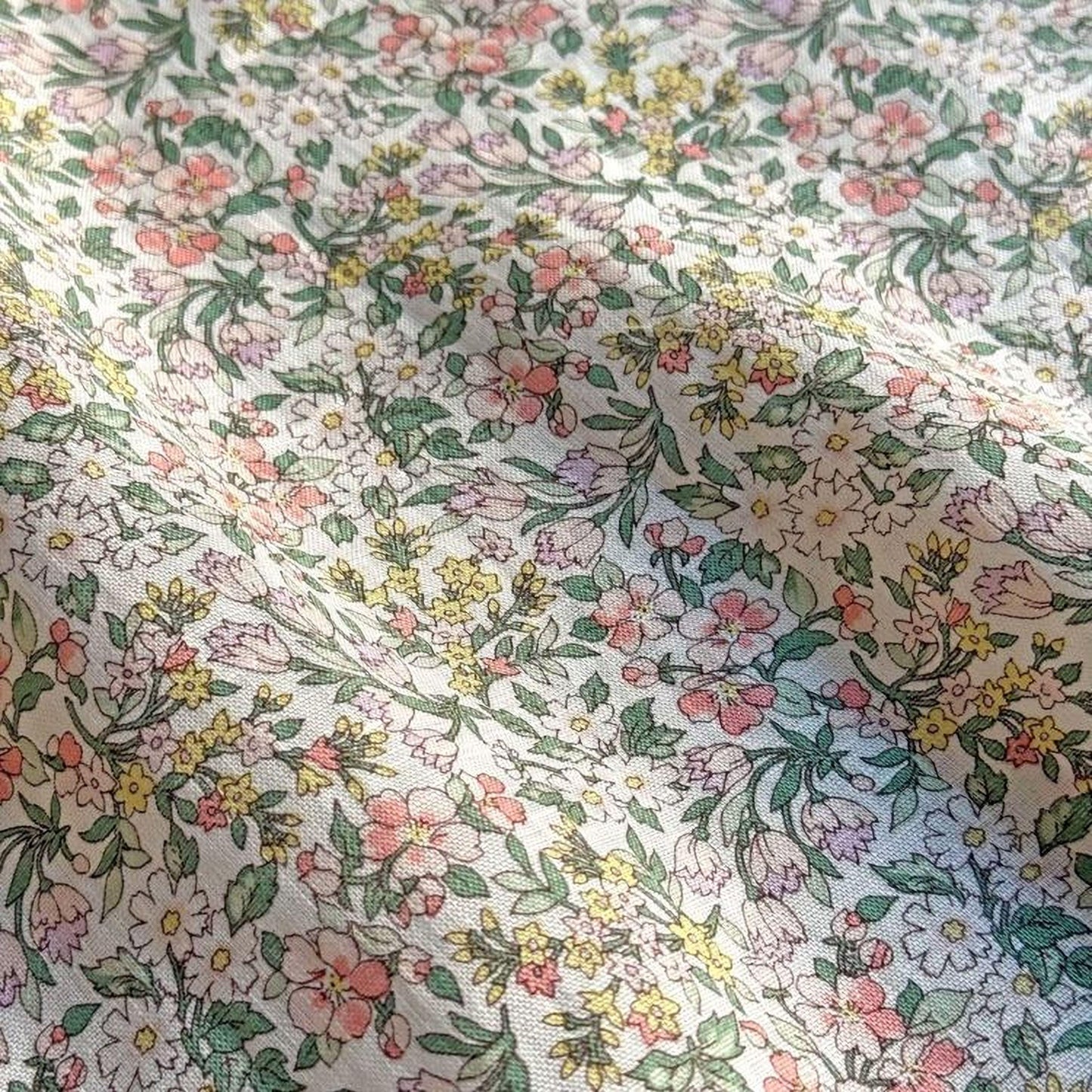a close-up view of a fabric with a floral pattern, featuring a variety of colorful flowers and leaves.