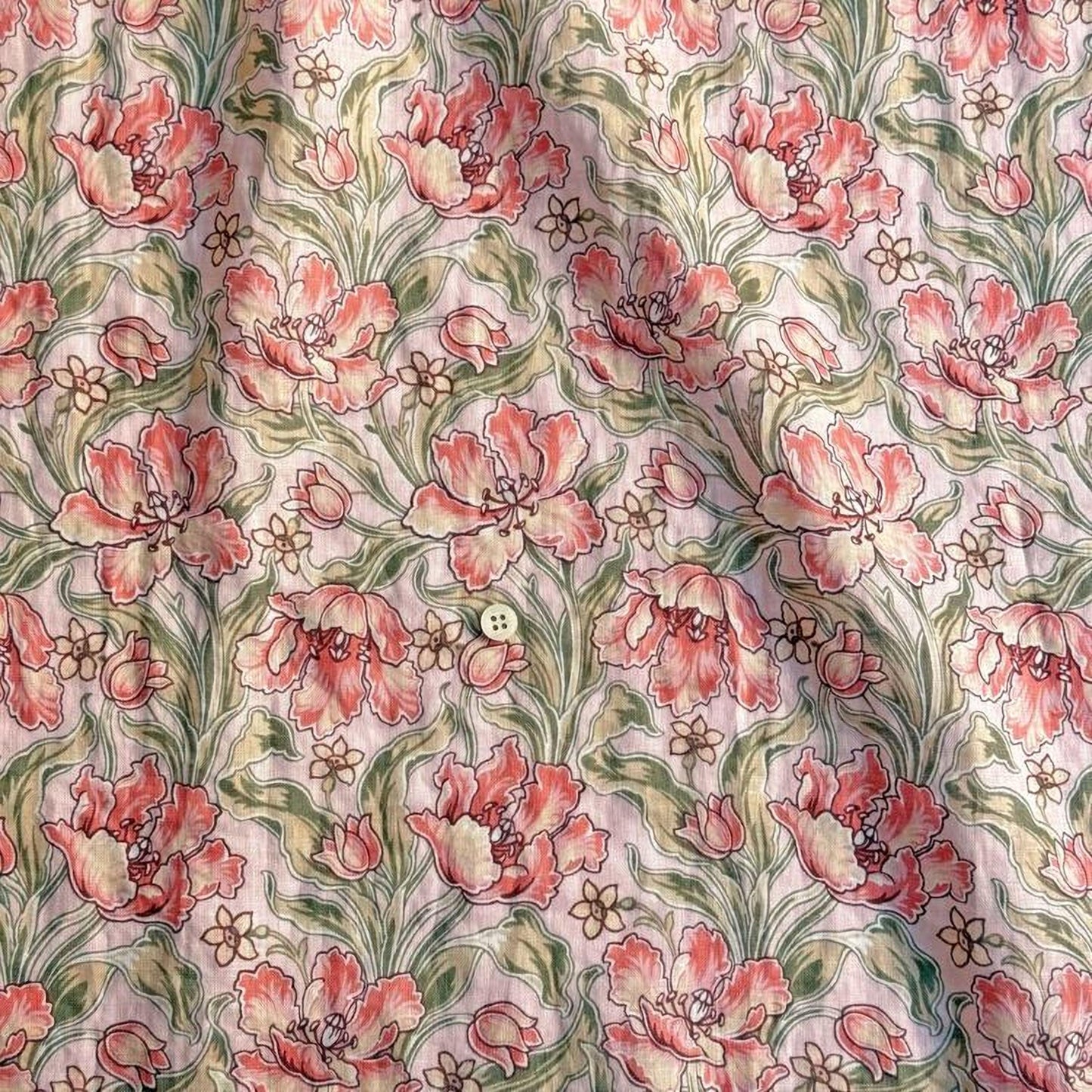 a close-up view of a fabric with a floral pattern. The pattern consists of pink flowers with green leaves, creating a visually appealing and intricate design. The fabric appears to be a light pink color, which complements the pink flowers and green leaves. The pattern repeats itself across the fabric, creating a sense of continuity and rhythm. The image does not contain any text or other objects, and the focus is solely on the floral pattern.