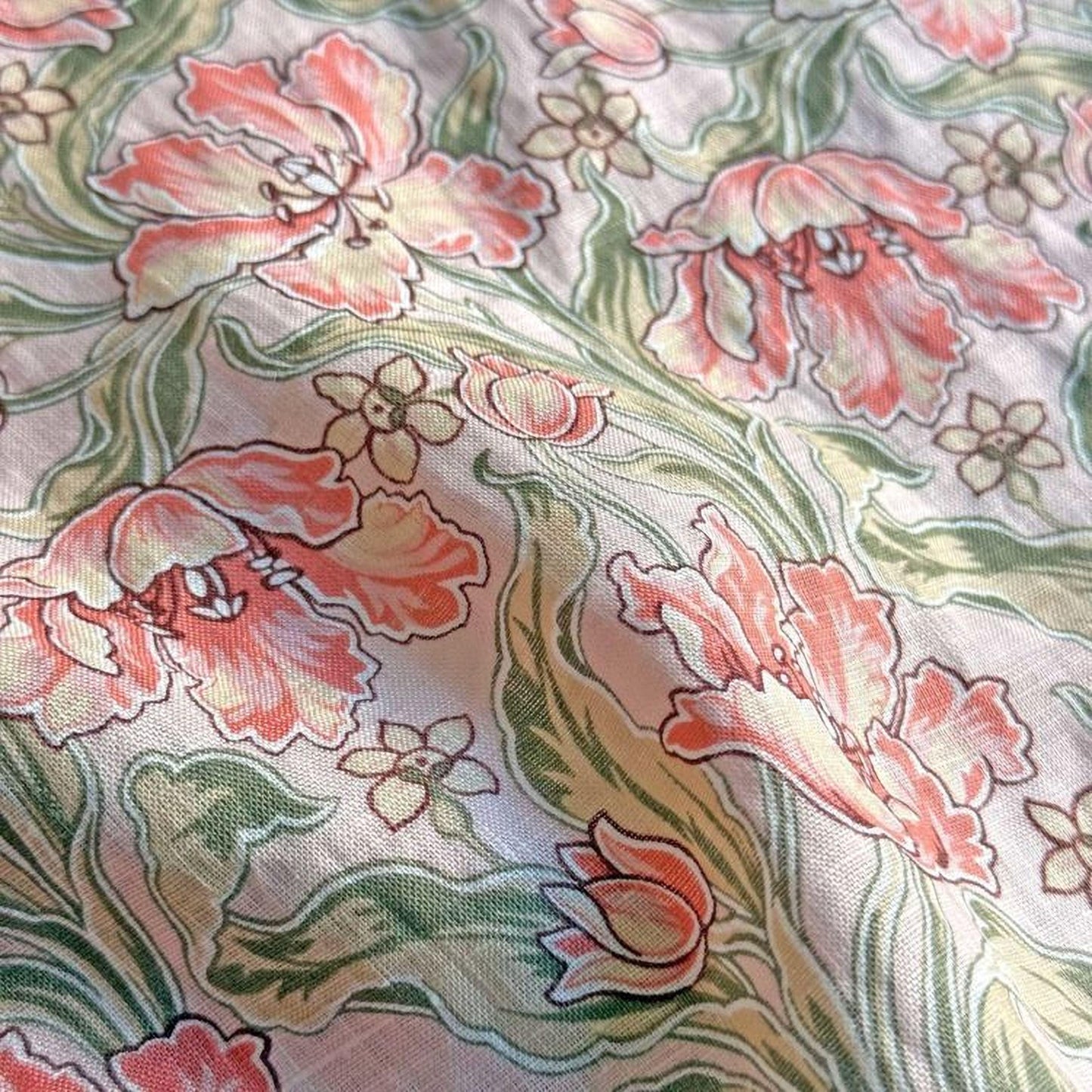 a close-up view of a fabric with a floral pattern. The pattern consists of various pink and green flowers, along with leaves and stems, creating a visually appealing and intricate design.