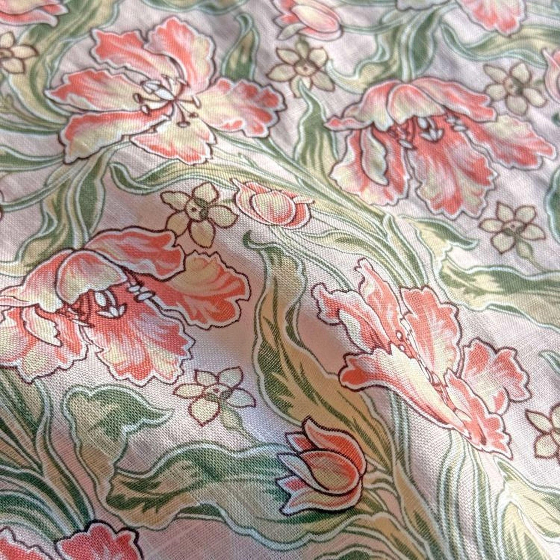 a close-up view of a fabric with a floral pattern. The pattern consists of various pink and green flowers, along with leaves and stems, creating a visually appealing and intricate design.