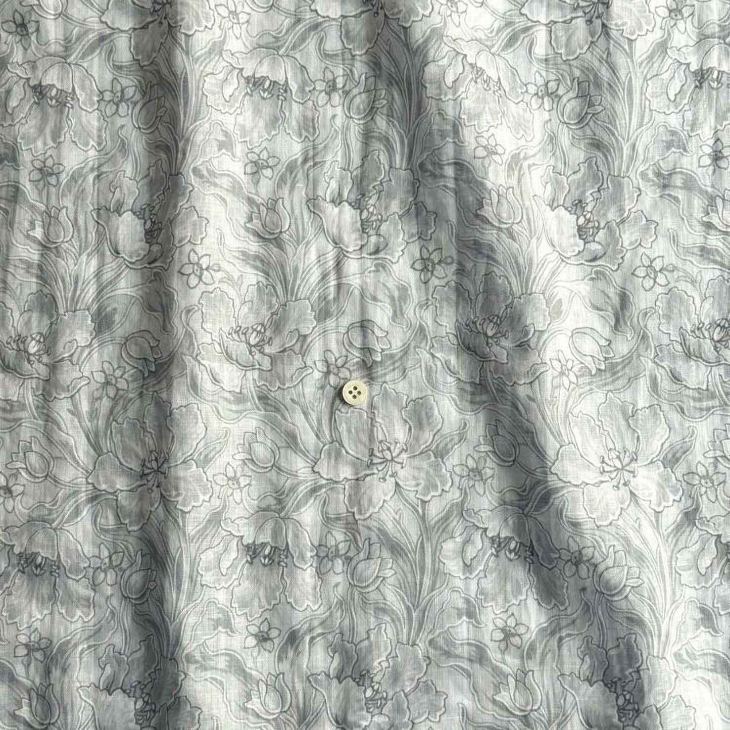 a close-up view of a fabric with a floral pattern, featuring a single button in the center.