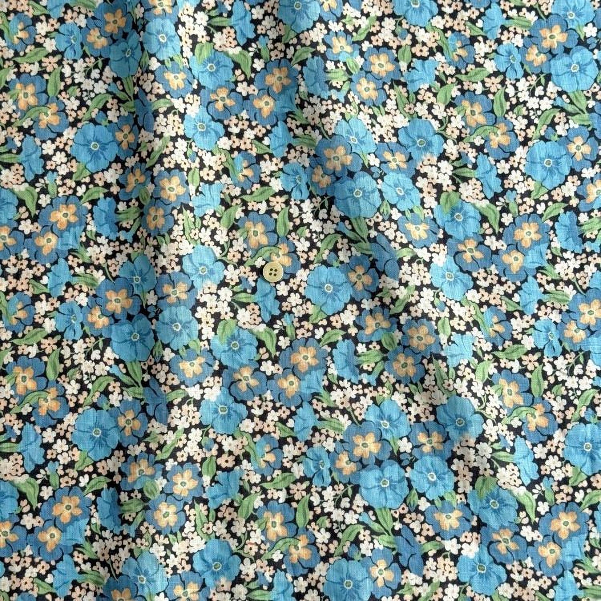 a close-up view of a fabric with a floral pattern. The fabric is predominantly blue and white, with blue flowers and leaves scattered throughout the fabric. The pattern is intricate and detailed, showcasing the craftsmanship of the fabric.