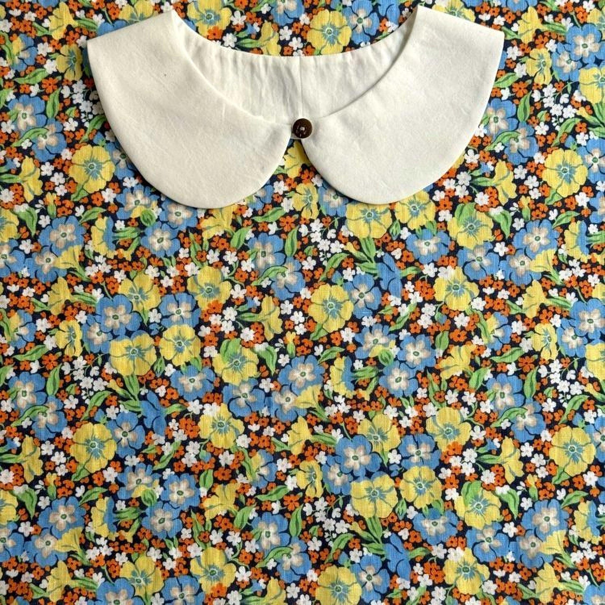 a white collar with a button, set against a background of a colorful floral print.