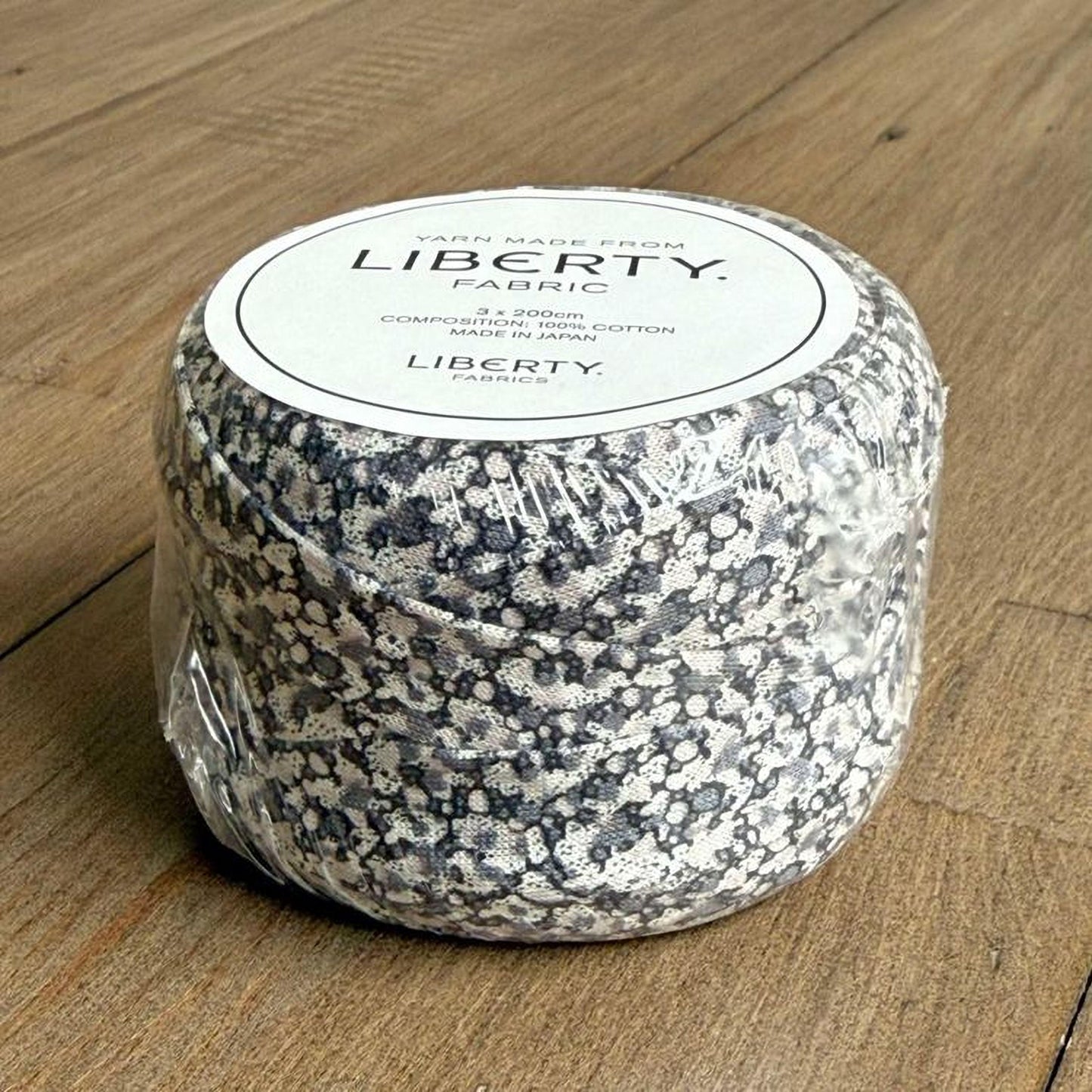 A package of Liberty Yarn made from fabric, sitting on a wooden surface.