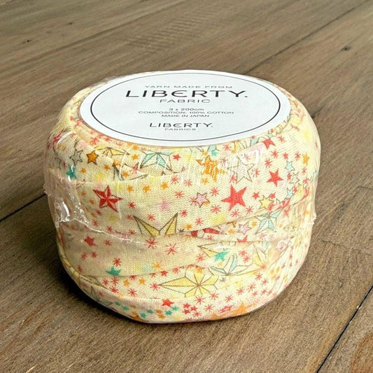 A package of fabric with a colorful star and flower pattern, sitting on a wooden surface.