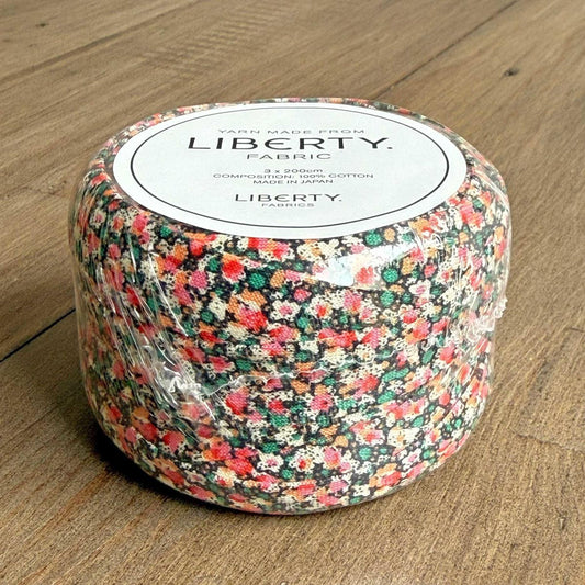 A package of fabric with a floral pattern, sitting on a wooden surface.