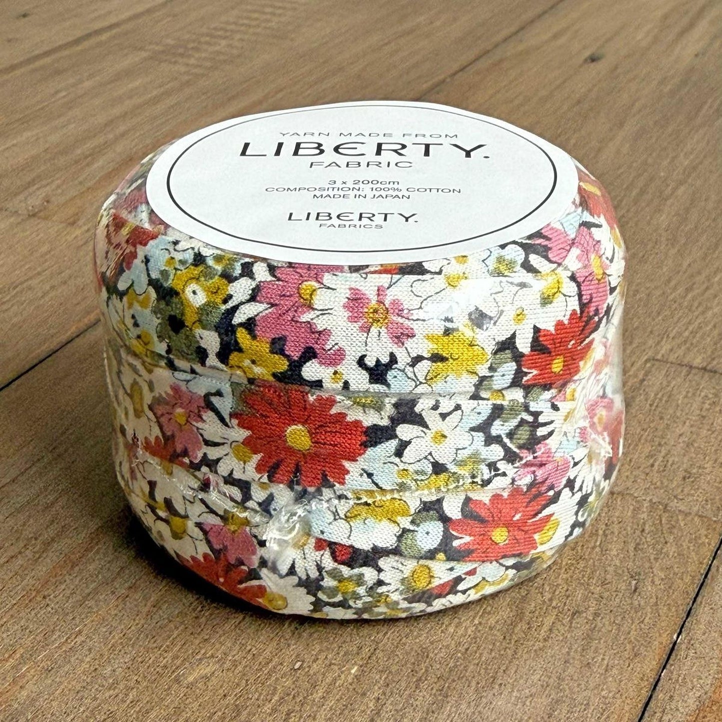 A container filled with a fabric that has a colorful floral pattern, sitting on a wooden surface.