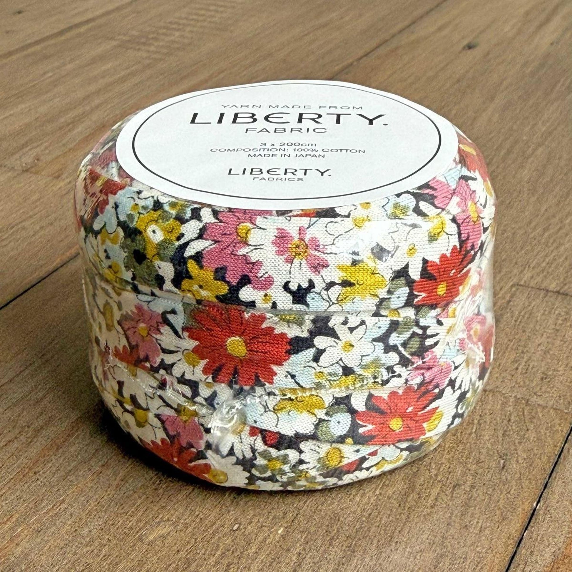 A container filled with a fabric that has a colorful floral pattern, sitting on a wooden surface.