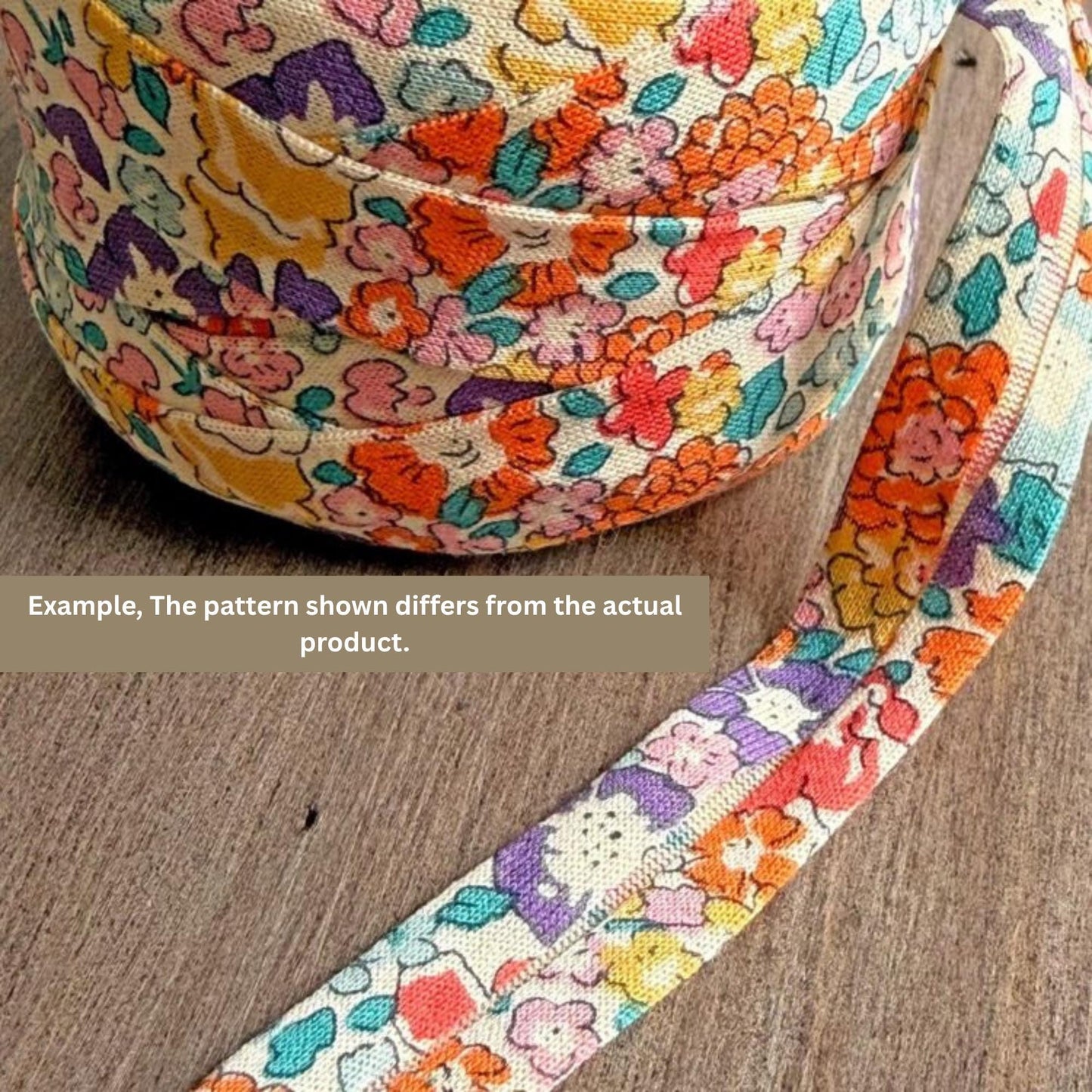 A spool of multicolored fabric with a floral pattern, lying on a wooden surface.