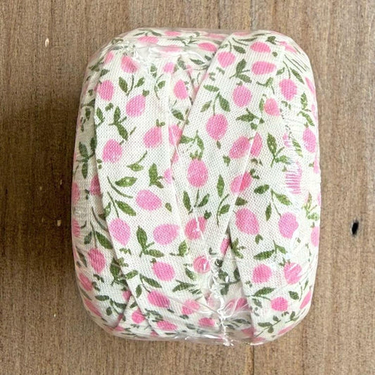 A roll of ribbon with a floral pattern in shades of pink and green.