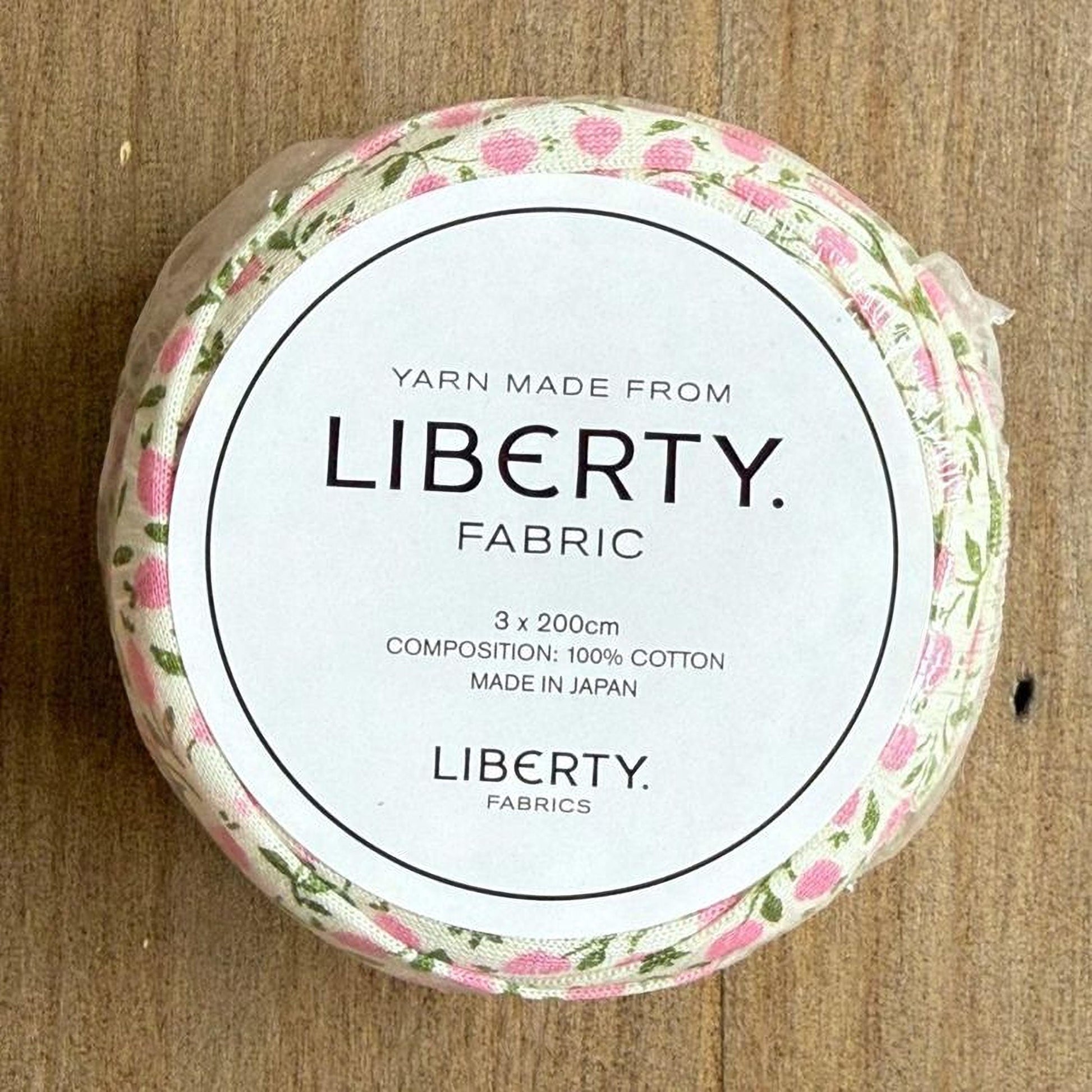 A round, white label with text and a floral pattern on a wooden surface.