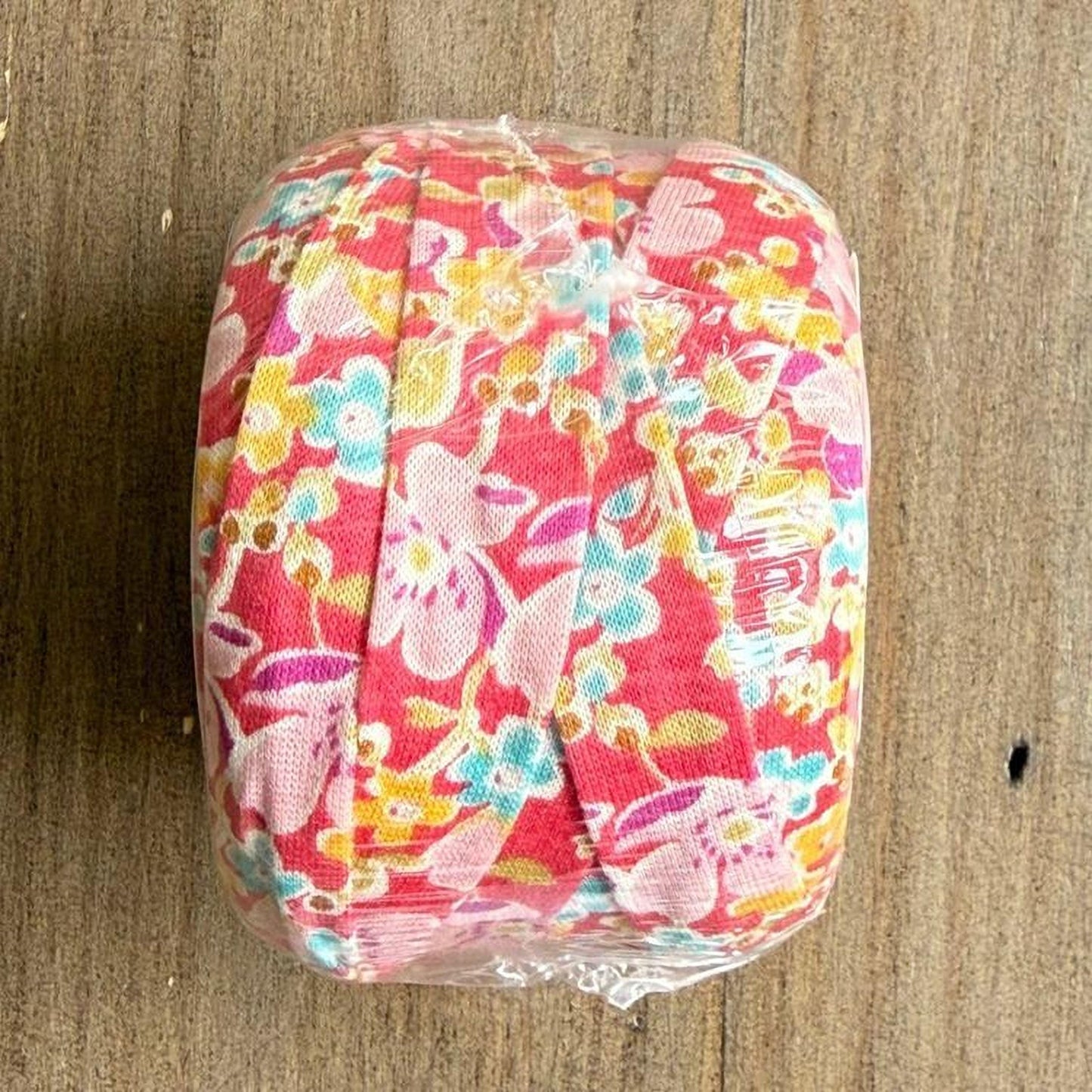A clear plastic bag containing a colorful floral fabric is placed on a wooden surface.