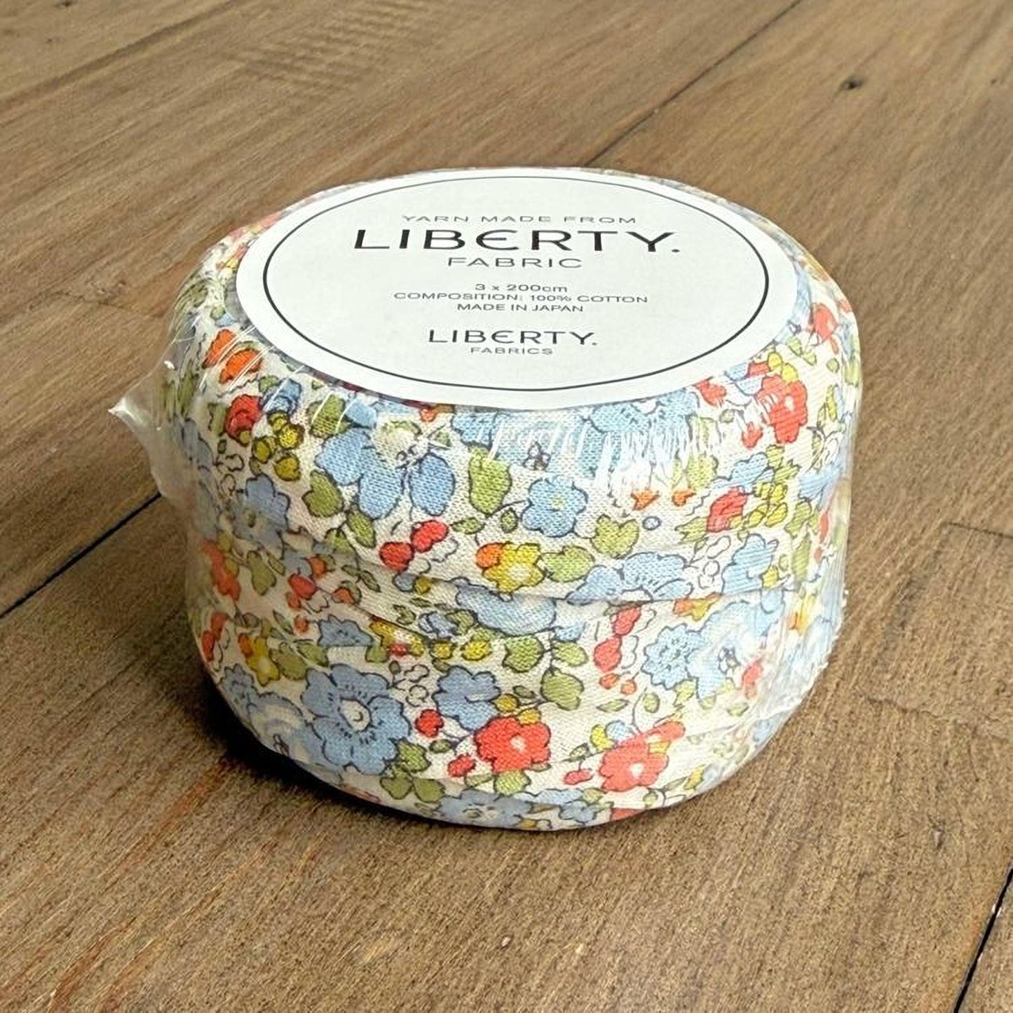 A round, white container with a floral pattern, sitting on a wooden surface.