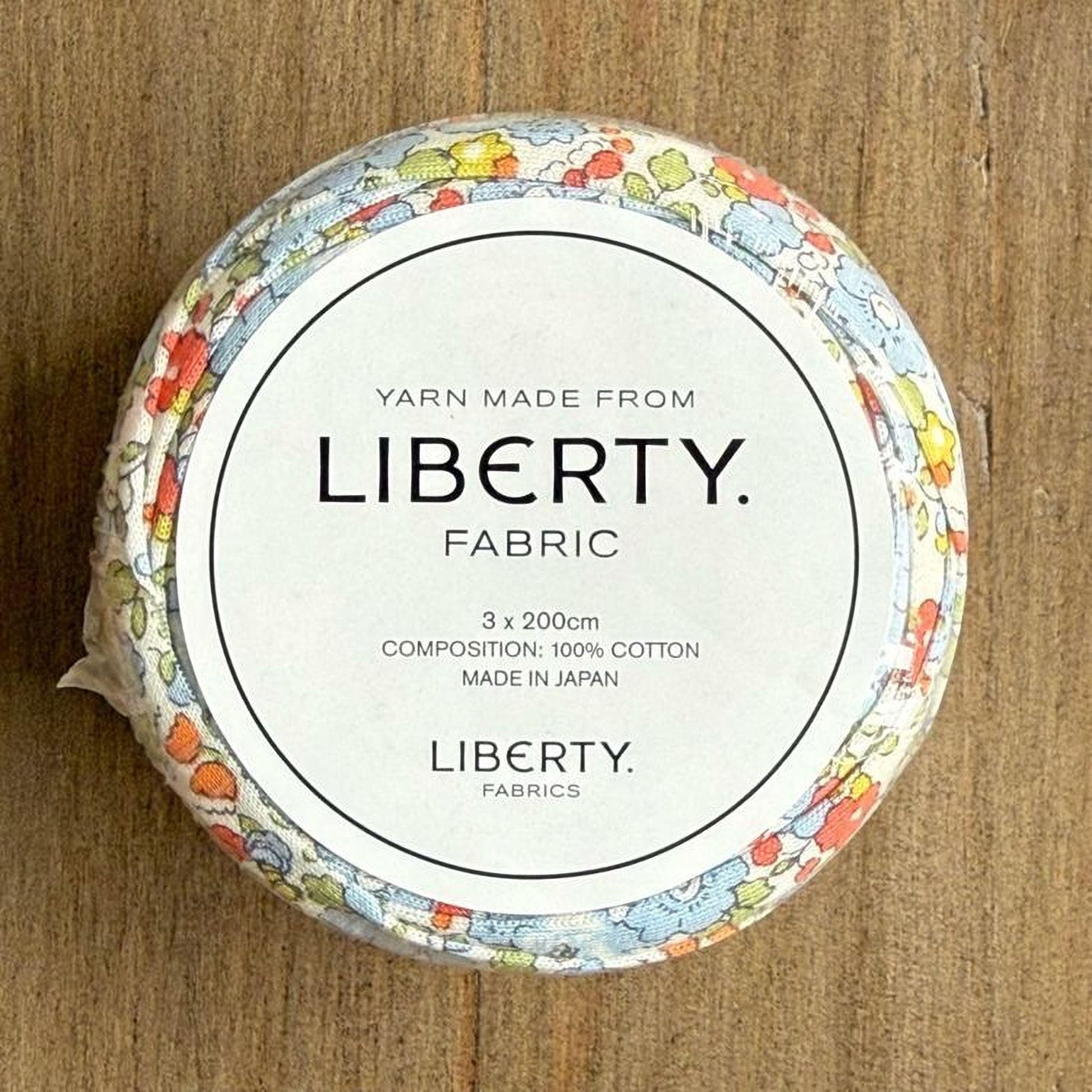 A circular container with a floral pattern and text on it, placed on a wooden surface.