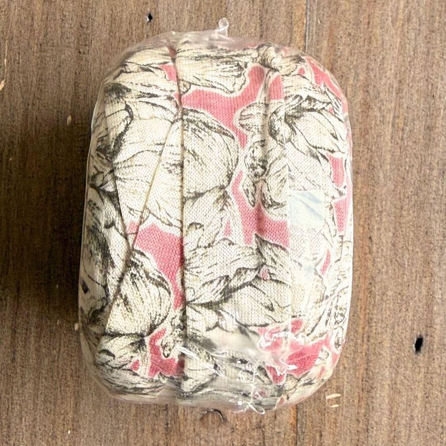 A clear plastic bag containing a floral patterned fabric, placed on a wooden surface.