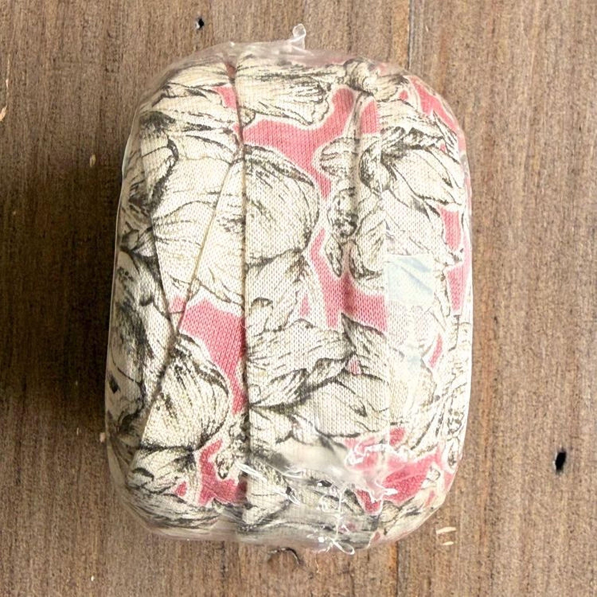 A clear plastic bag containing a floral patterned fabric, placed on a wooden surface.