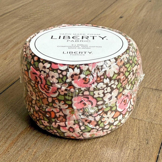 A roll of fabric with a floral pattern, labeled as "Liberty Fabric" and "Yarn Made from Liberty".