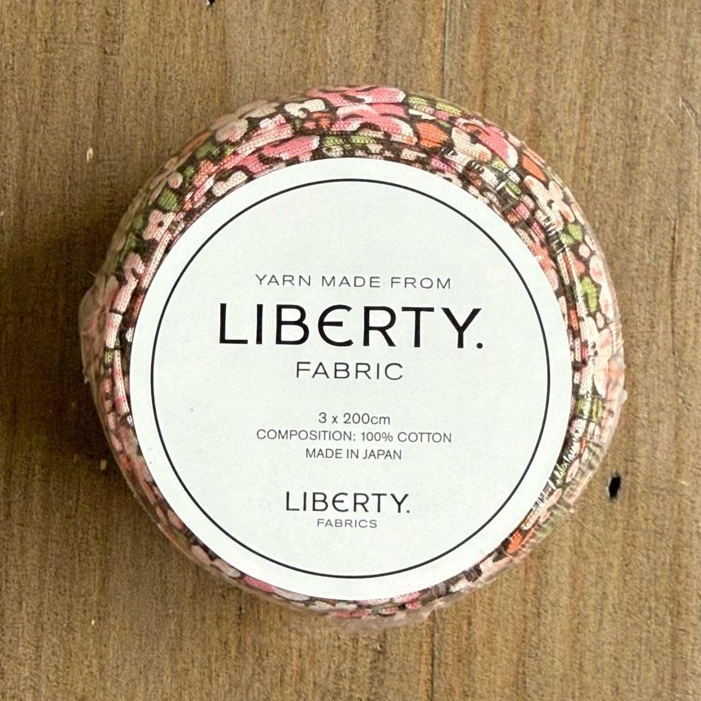 A round container with a label that reads "Yarn Made from LIBERTY. FABRIC" and "3 x 200m COMPOSITION: 100% COTTON MADE IN JAPAN".
