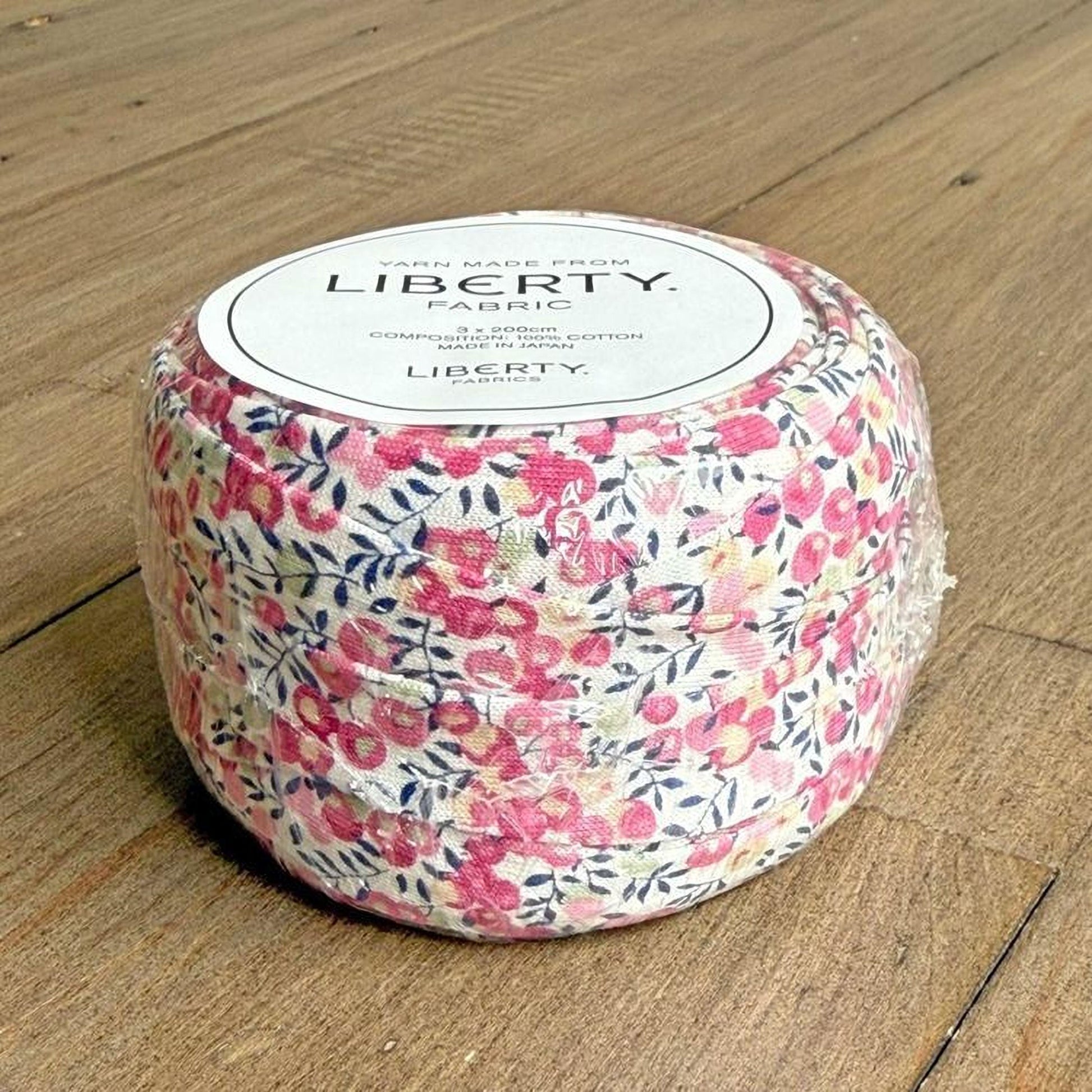 A package of fabric with a floral pattern, sitting on a wooden surface.