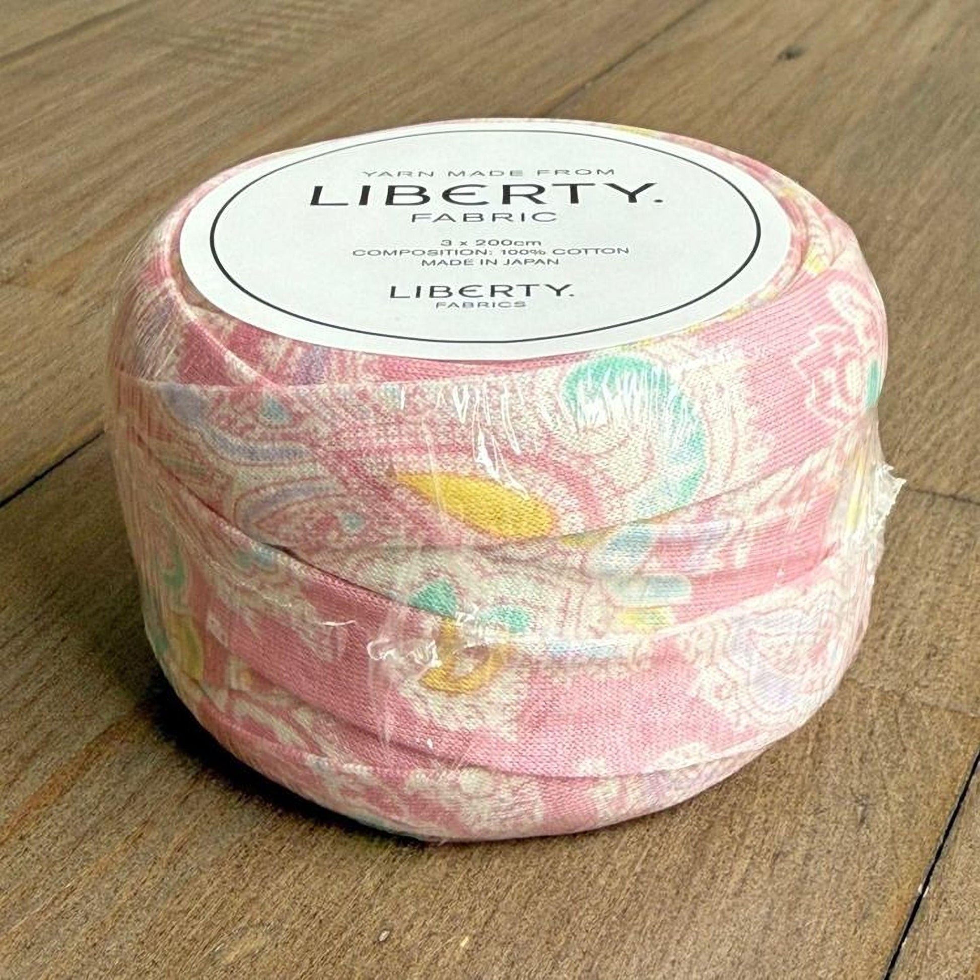 A spool of yarn made from Liberty fabric, with a label indicating it is 3.2 yards in length and made in Japan.