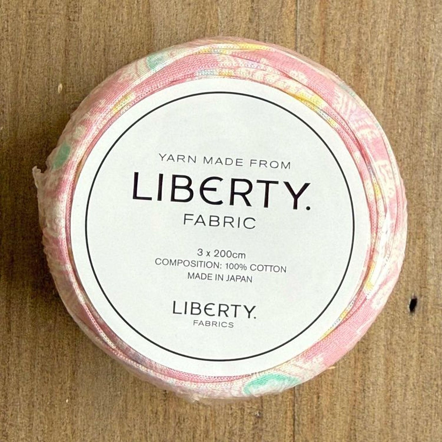 A spool of yarn made from Liberty fabric, with a label indicating it is 3 x 200cm in composition, 100% cotton, and made in Japan.