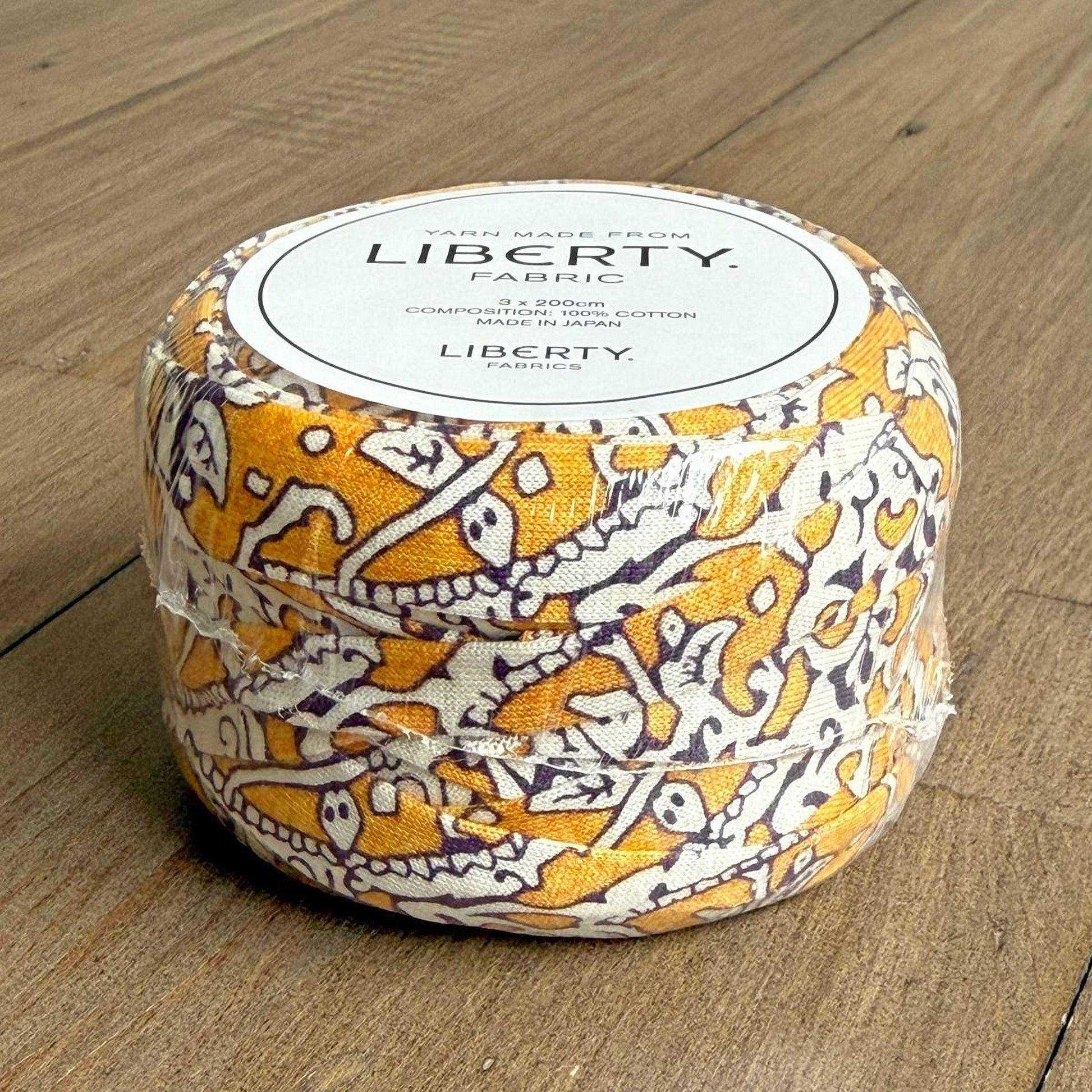 A cylindrical container with a label that reads "Yarn Made from LIBERTY Fabric" and "3.5 oz. 100% cotton yarn".