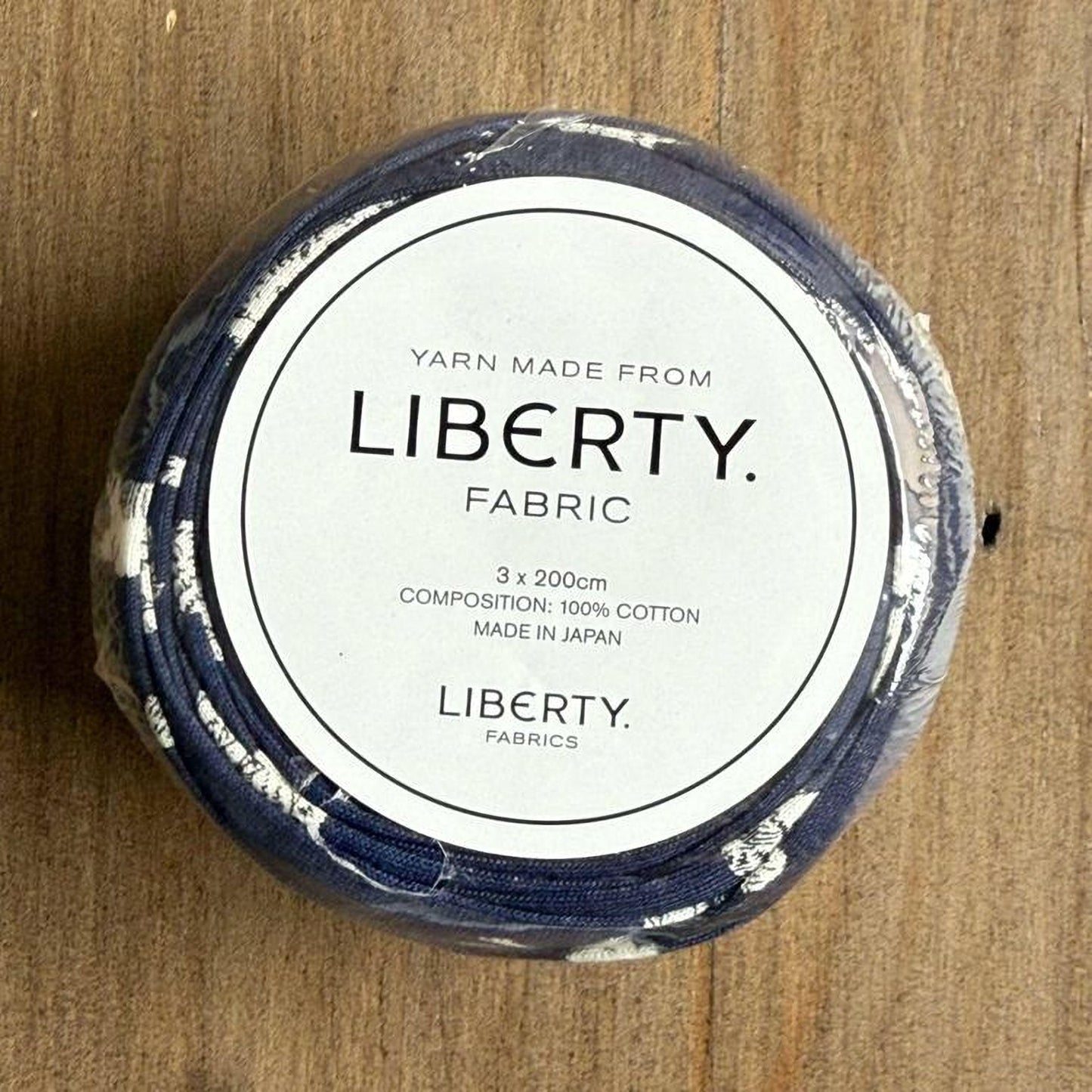 A spool of yarn made from Liberty fabric, with a label indicating it is 3.2 yards (200 cm) in length and made in Japan.