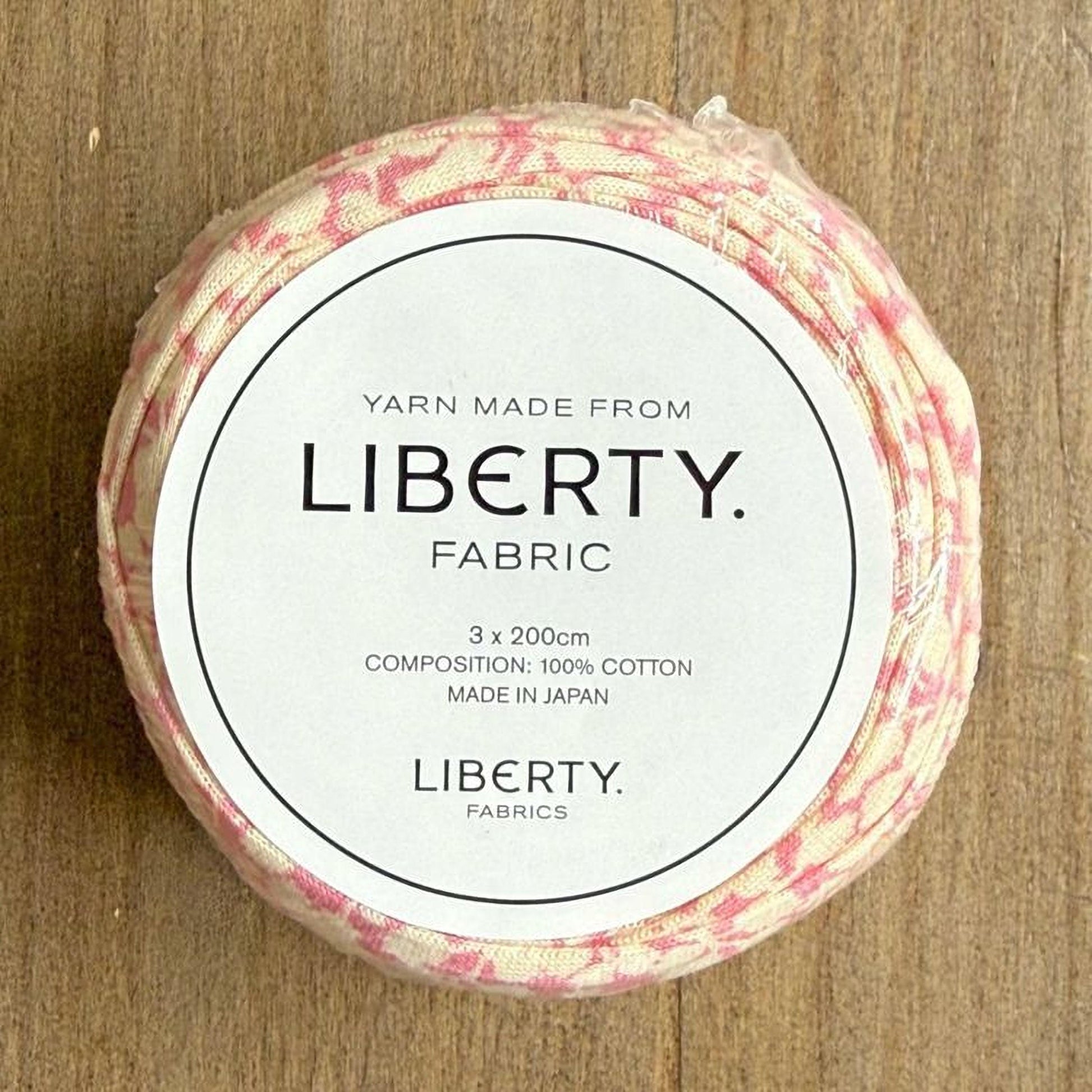 A circular piece of fabric with a label that reads "Yarn Made from LIBERTY. FABRIC 3 x 200cm COMPOSITION: 100% COTTON MADE IN JAPAN LIBERTY. FABRICS".
