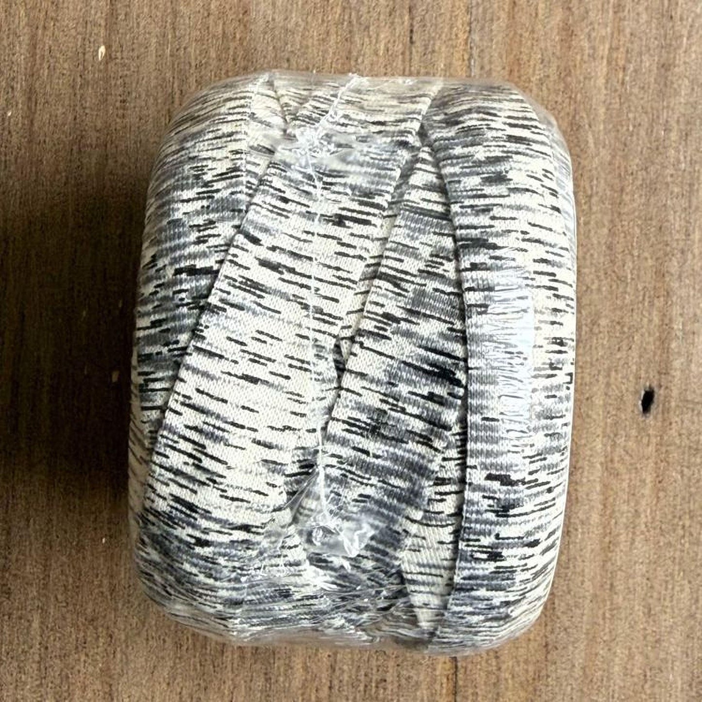 A roll of black and white striped fabric is placed on a wooden surface.