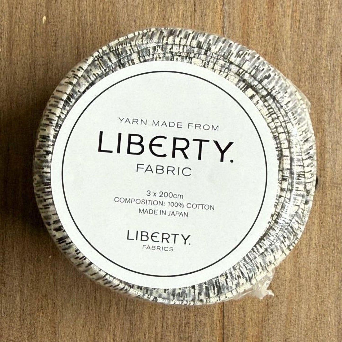 A white label with black text on a circular background, indicating that the yarn is made from Liberty fabric and is 3x 200cm in size, made in Japan.