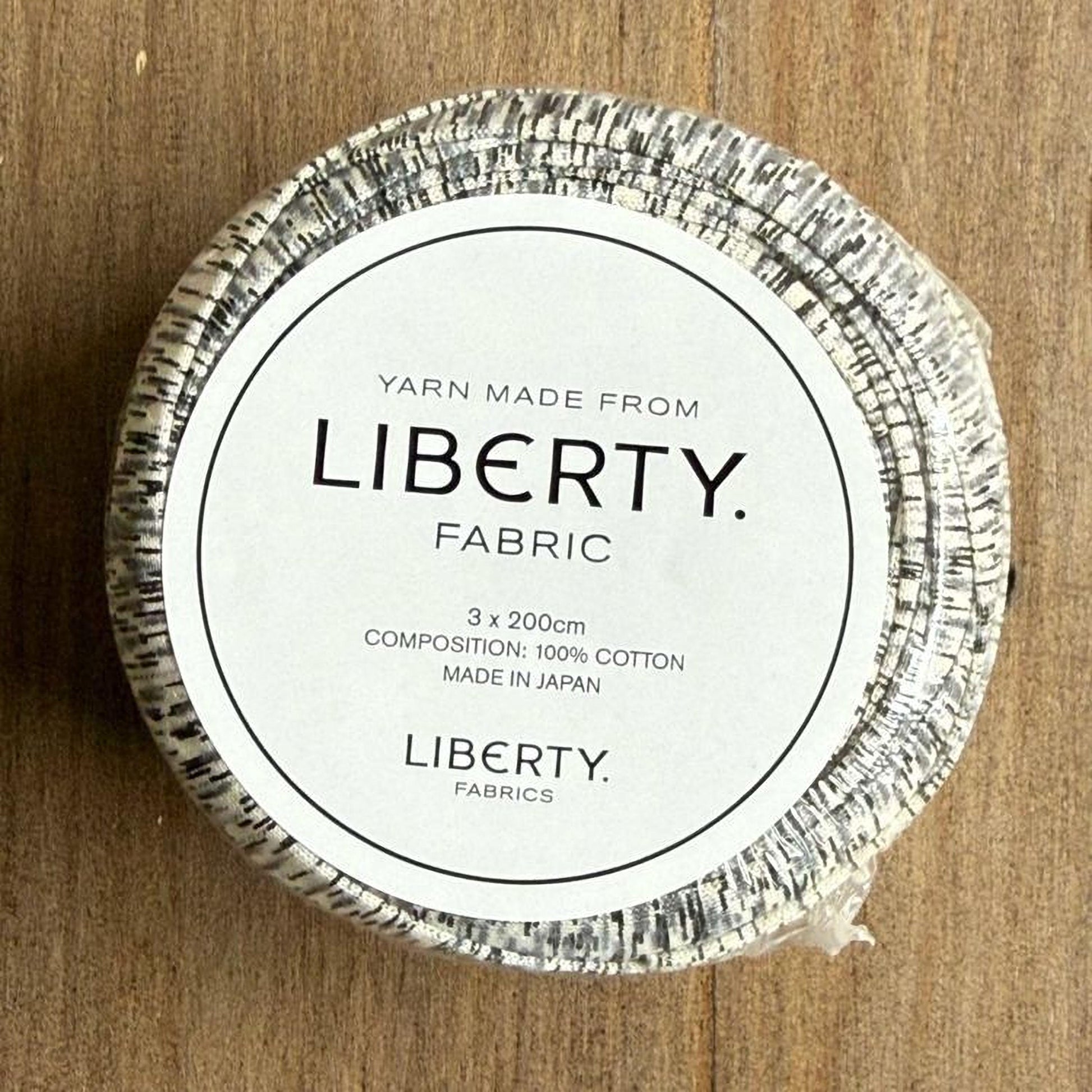 A white label with black text on a circular background, indicating that the yarn is made from Liberty fabric and is 3x 200cm in size, made in Japan.