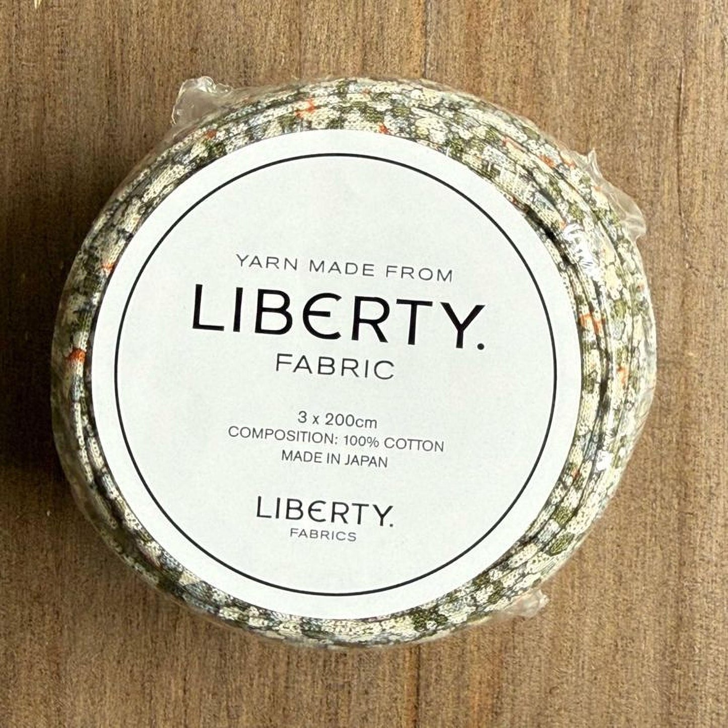 A white label with black text on a circular background, which appears to be a product label for a yarn made from fabric.