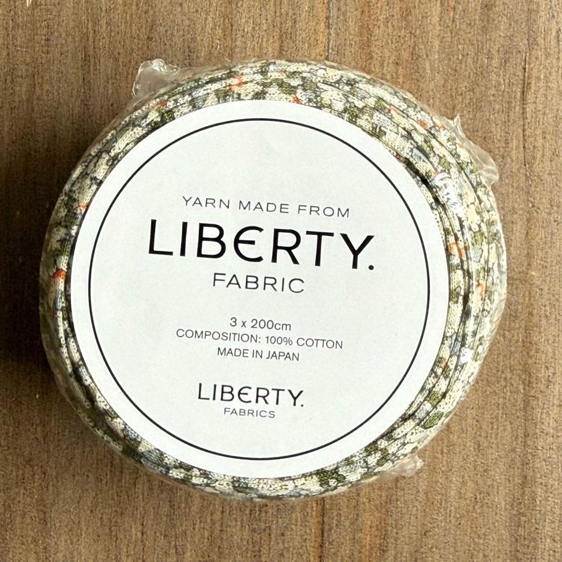 A white label with black text on a circular background, which appears to be a product label for a yarn made from fabric.