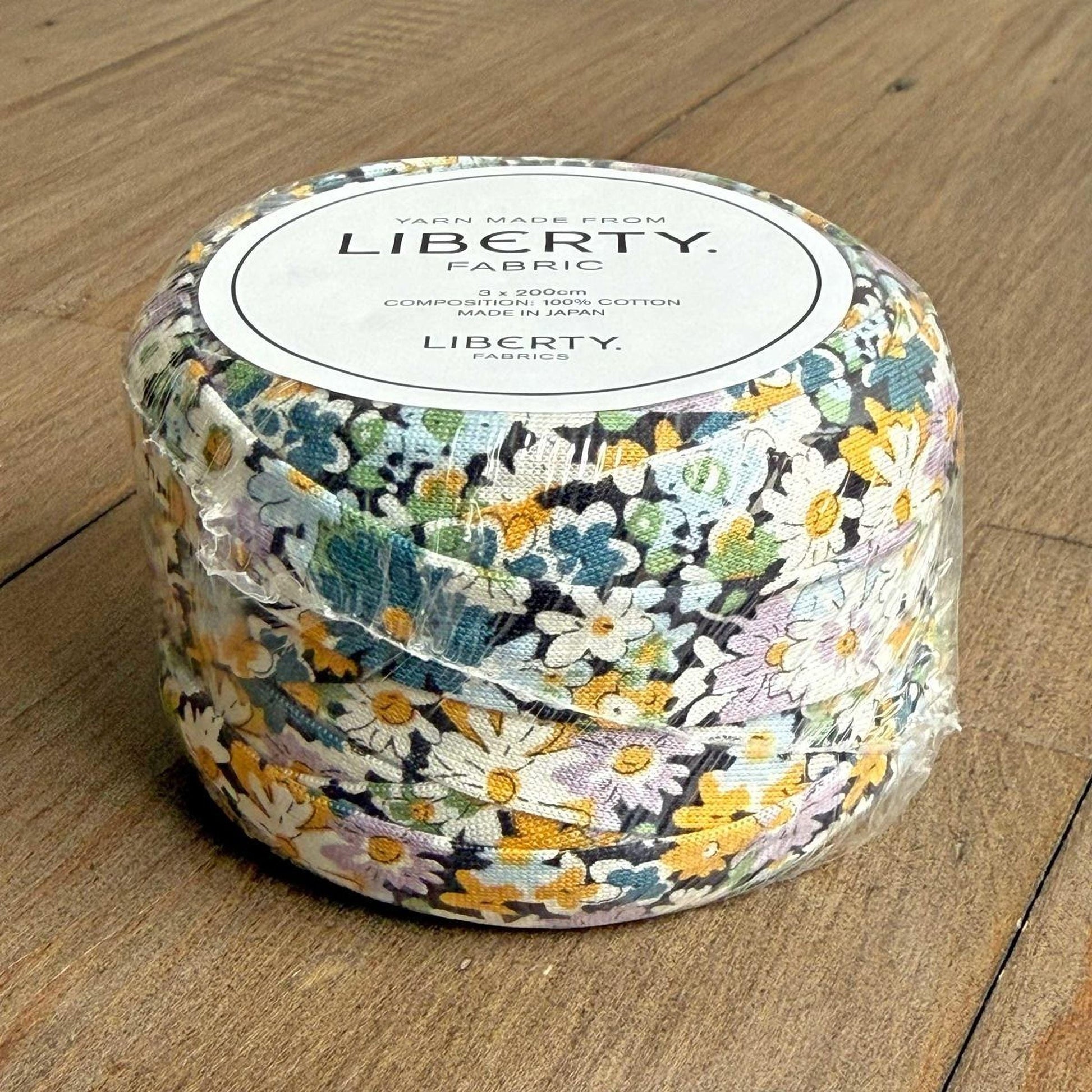A package of Liberty fabric, featuring a floral print in shades of blue, green, and yellow.