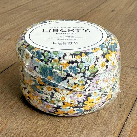 A package of Liberty fabric, featuring a floral print in shades of blue, green, and yellow.