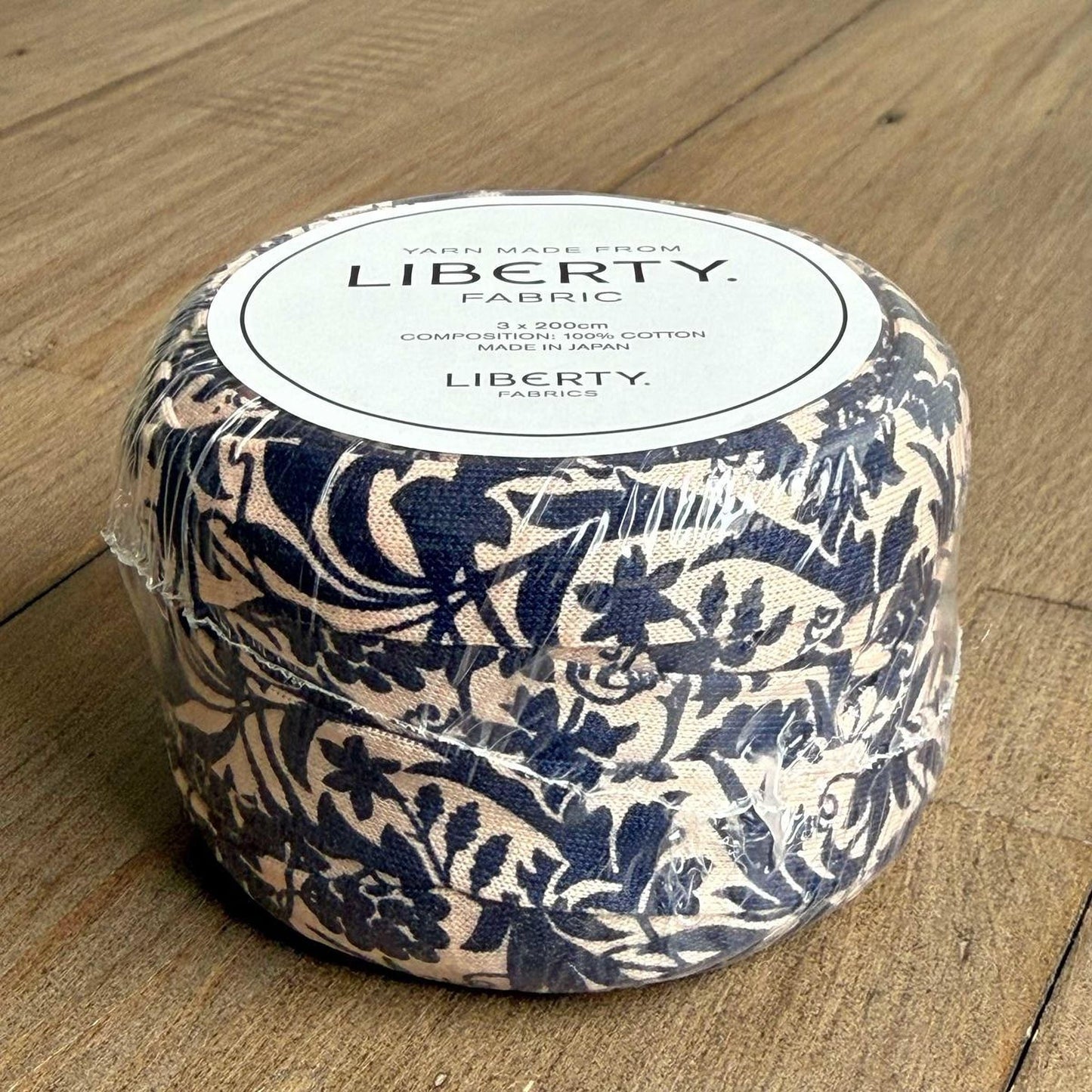 A package of fabric with a floral pattern, sitting on a wooden surface.