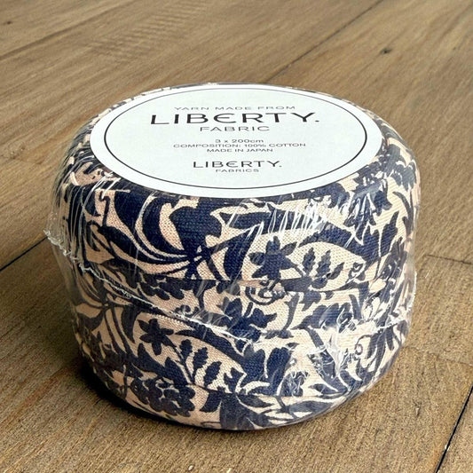 A package of fabric with a floral pattern, sitting on a wooden surface.