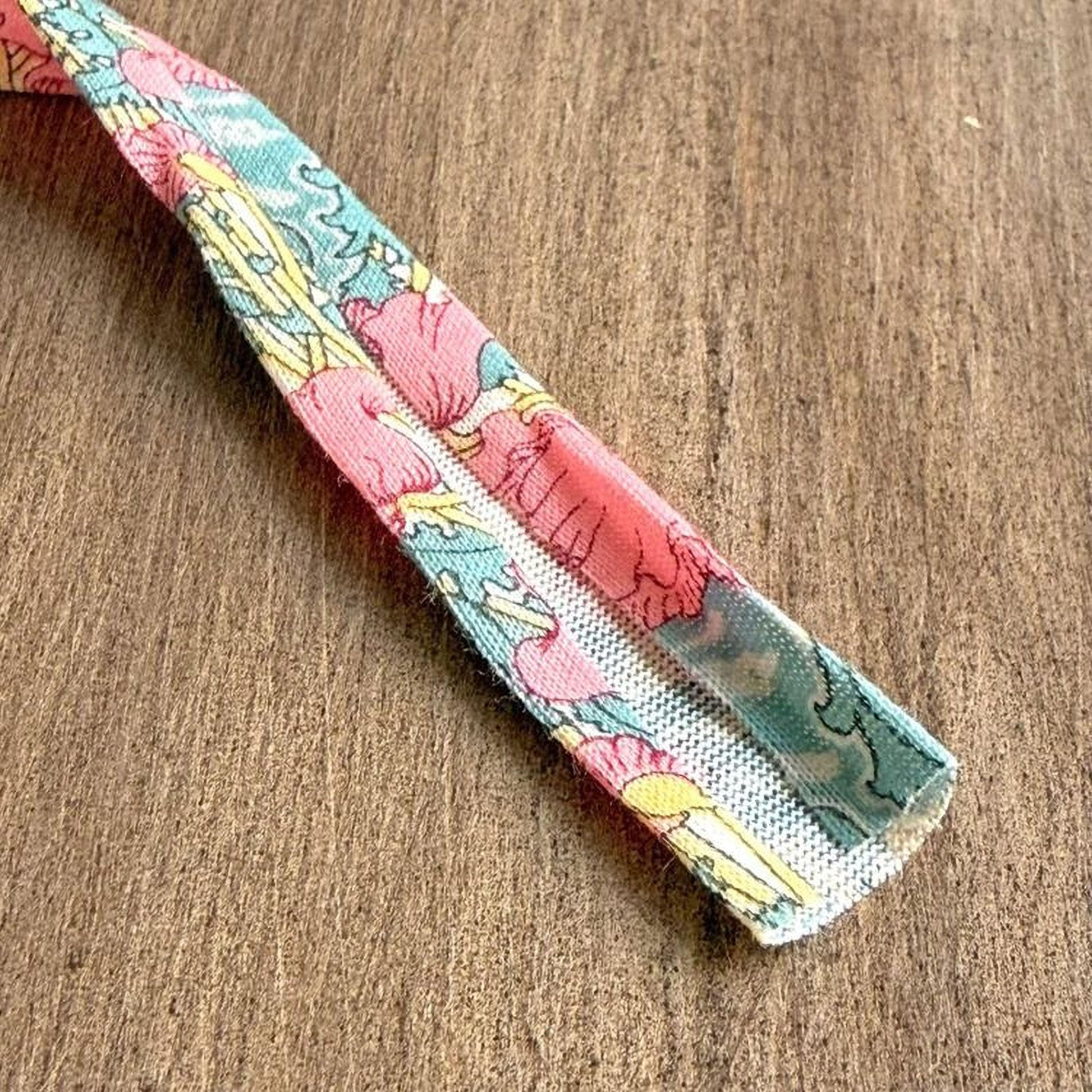 A colorful fabric with a floral pattern is lying on a wooden surface.