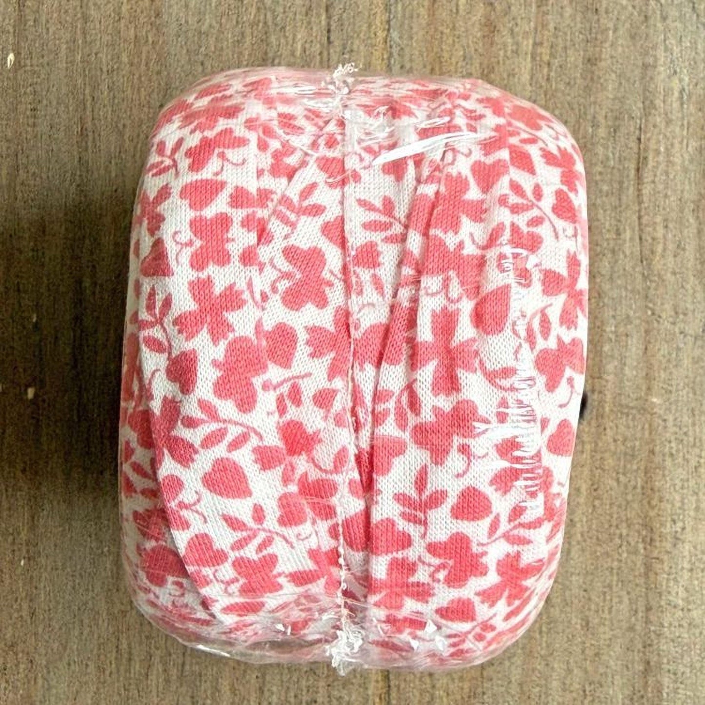 A clear plastic bag with a red and white floral pattern is placed on a wooden surface.
