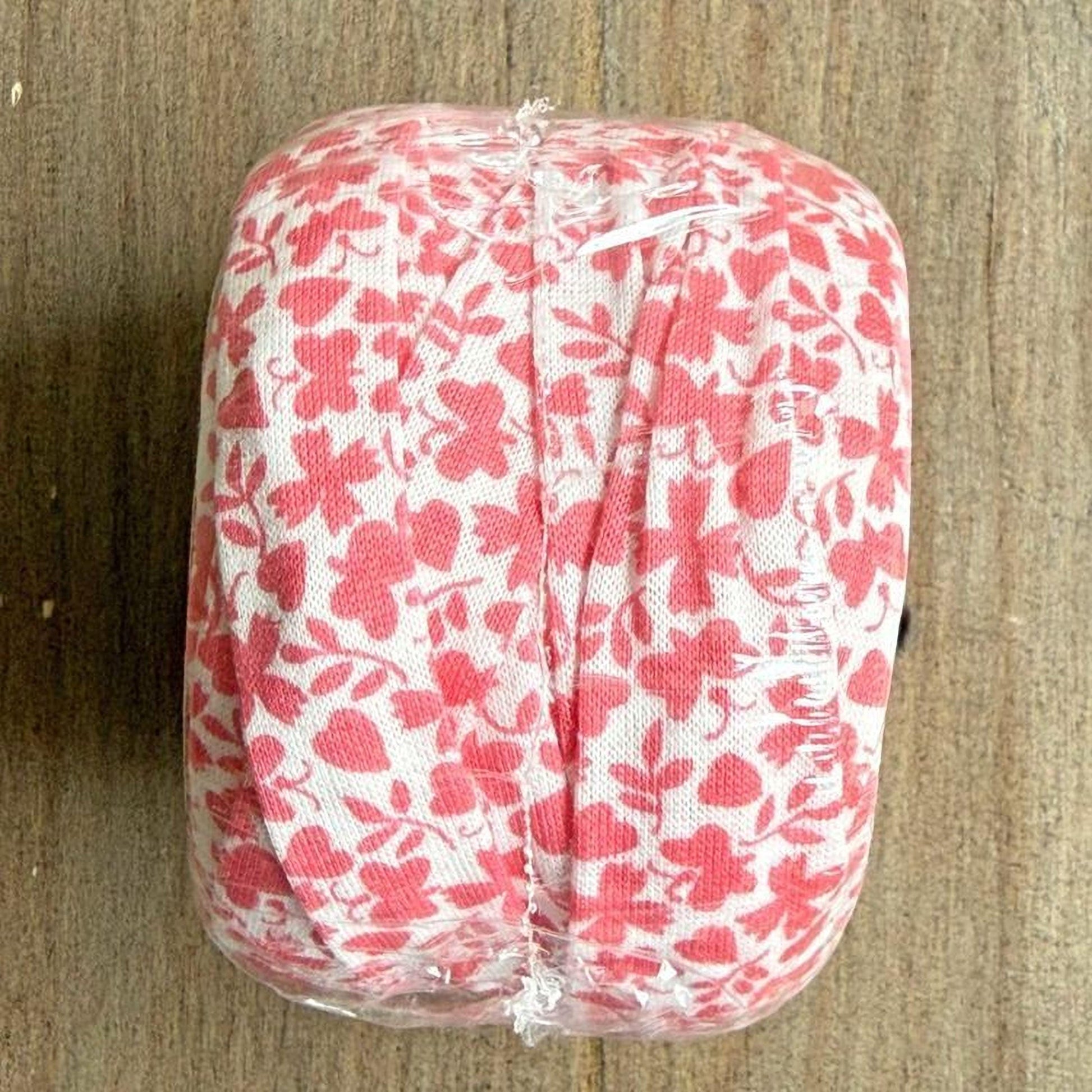 A clear plastic bag with a red and white floral pattern is placed on a wooden surface.
