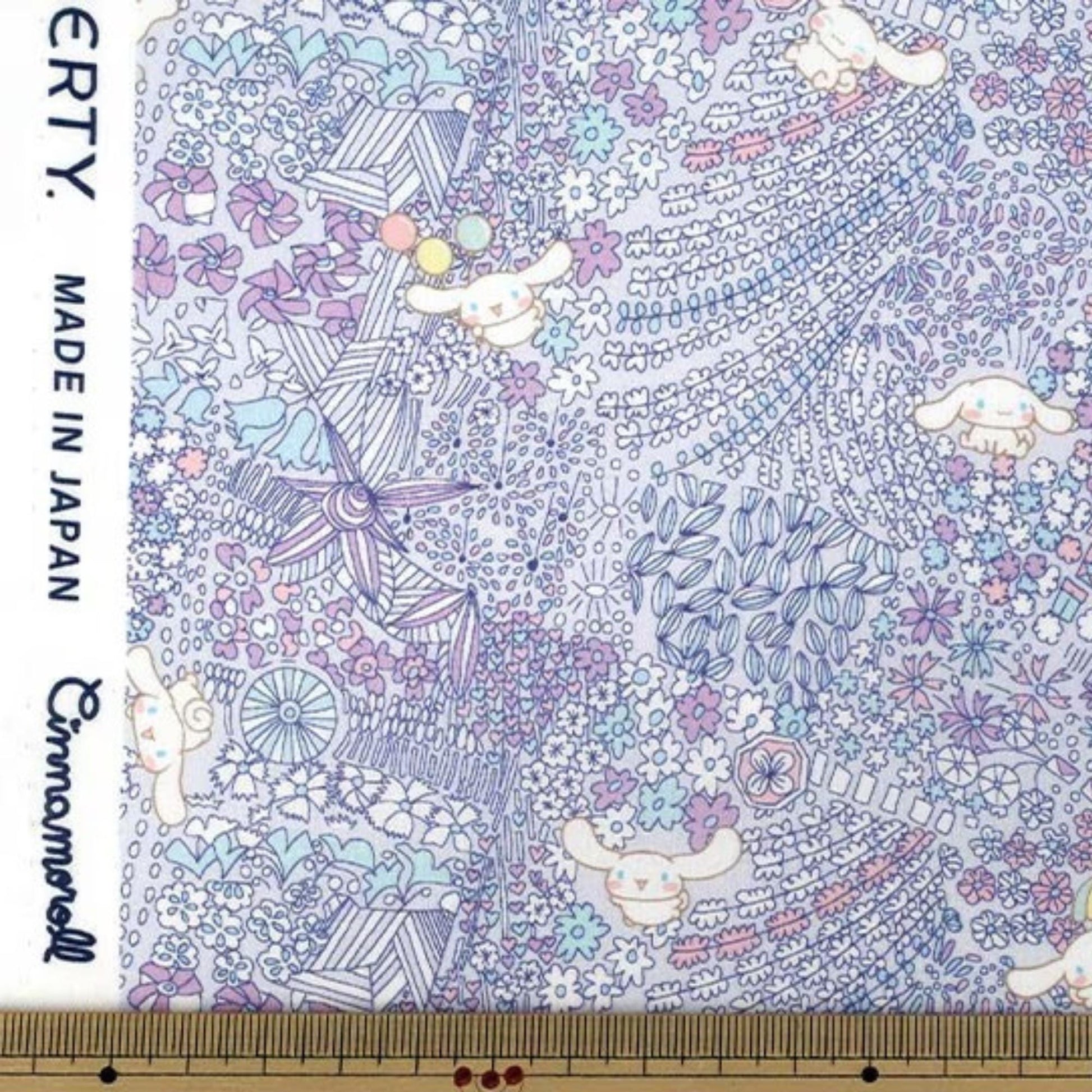 The image is a fabric with a colorful, whimsical pattern featuring various cartoon-like characters and floral designs.