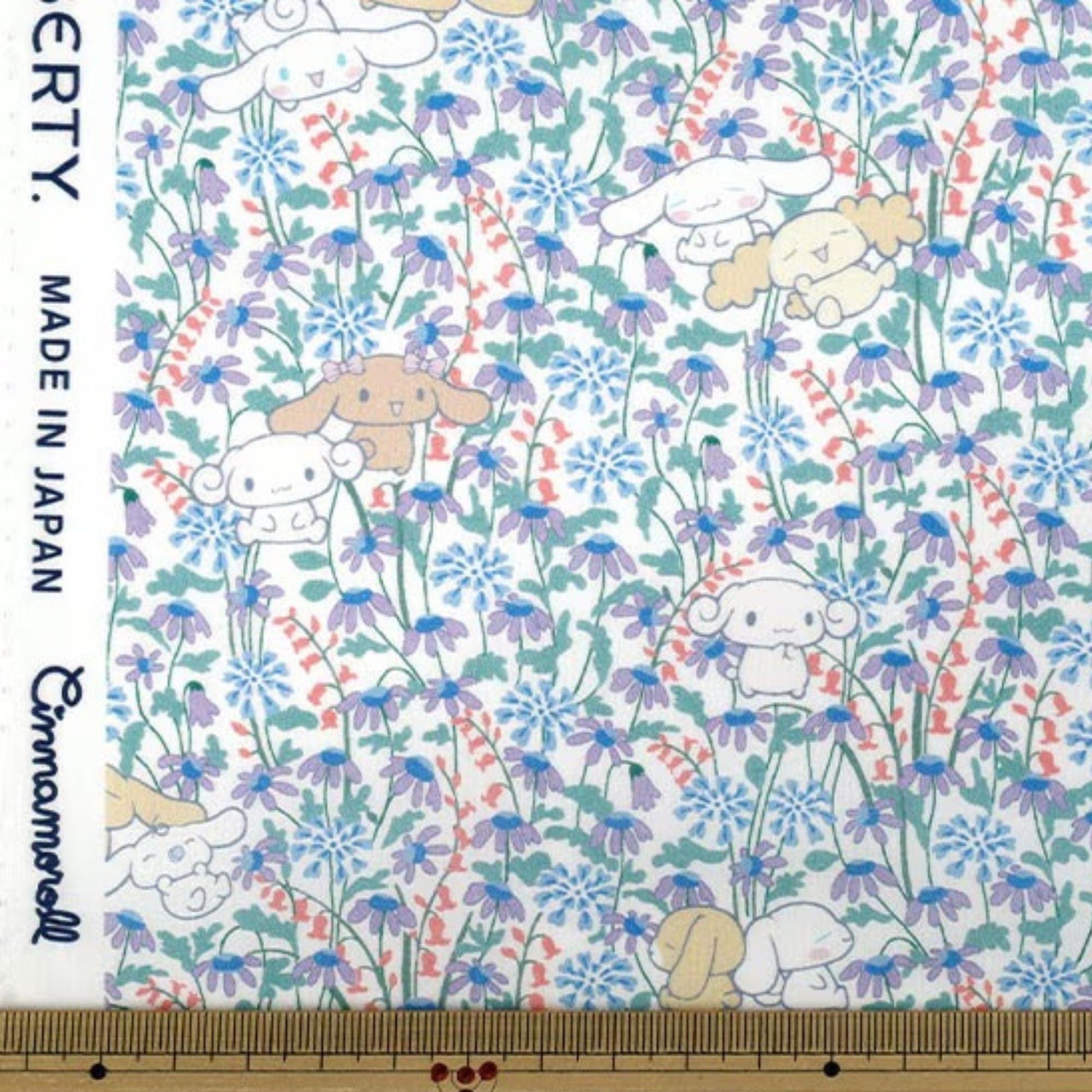 The image is a fabric print featuring a floral pattern with various cartoon-like animals, including rabbits, flowers, and other whimsical elements. The print is predominantly white with blue and purple accents, creating a visually appealing and playful design.