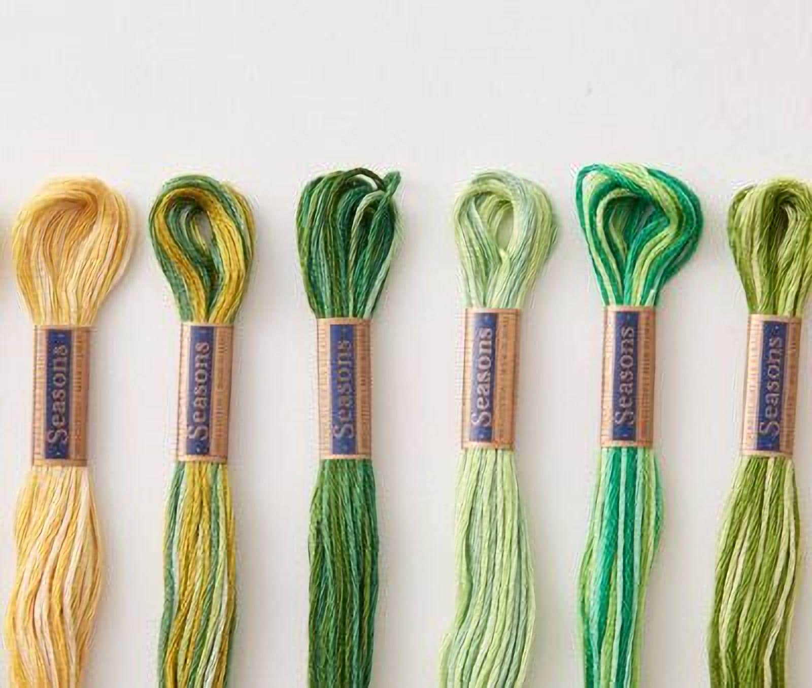A collection of six spools of thread in various colors, including yellow, green, and blue, arranged on a white background.