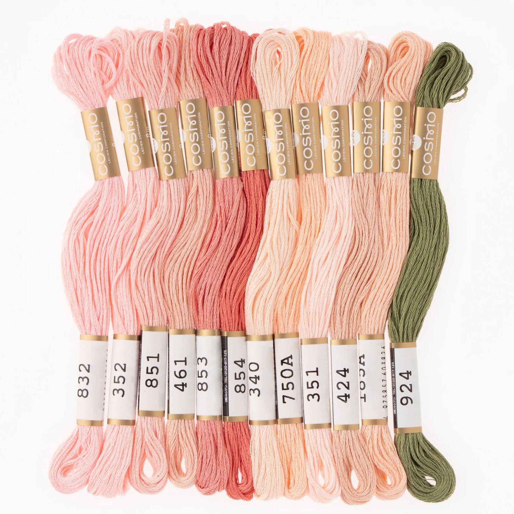 A collection of various colored embroidery floss threads, including pink, peach, green, and other pastel shades, arranged in rows.